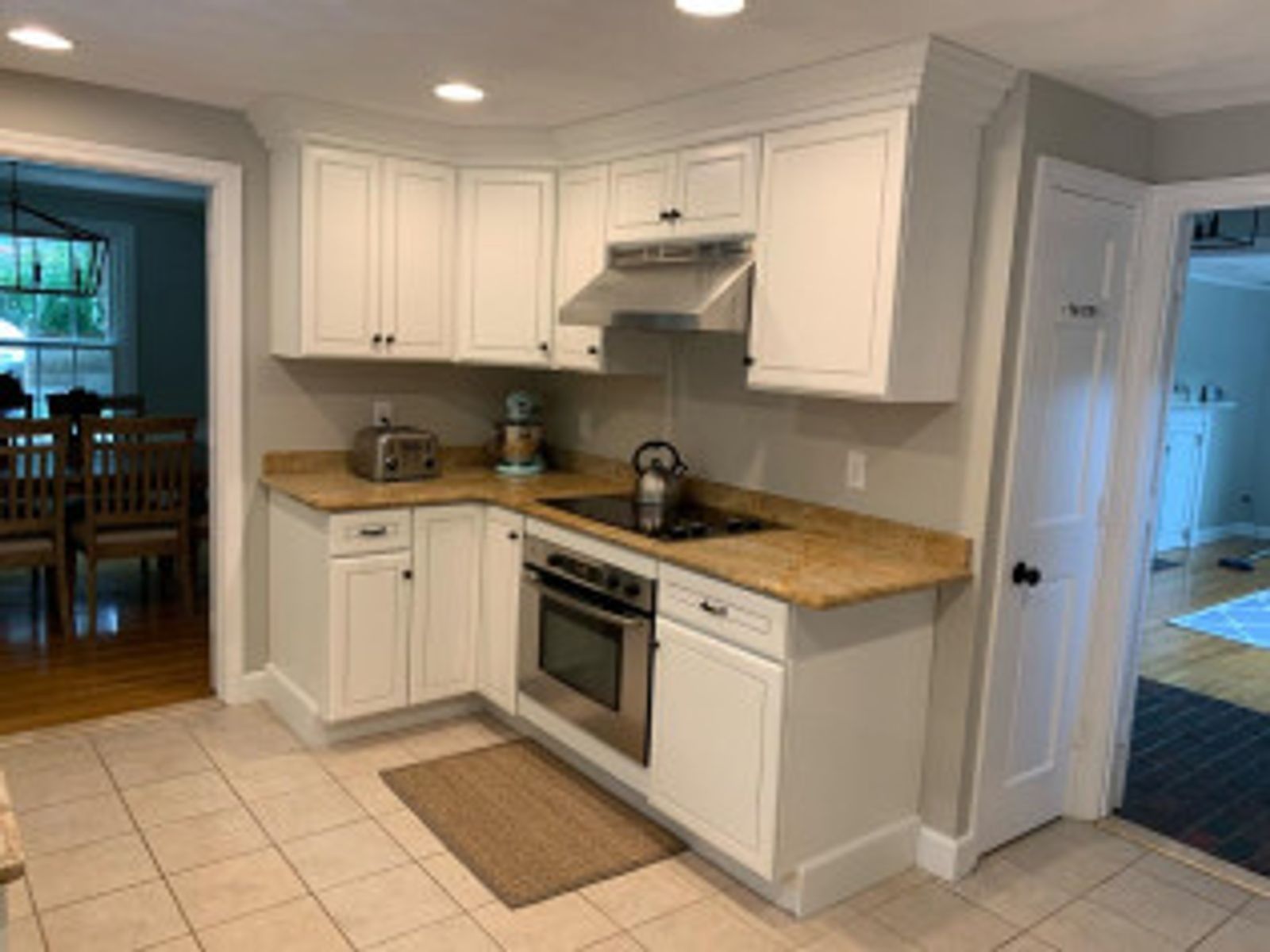 White kitchen cabinets in a corner with a stovetop, oven, and granite countertops.