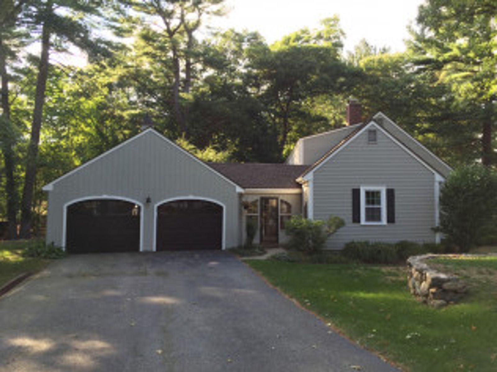 Gray house with attached two-car garage, brown roof, black garage doors, and a driveway.