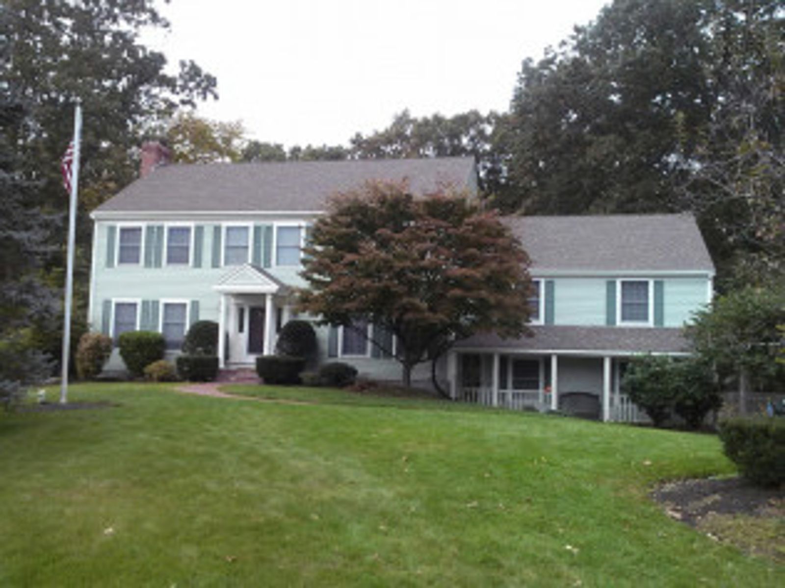 Two-story house with light green siding and a green lawn under an overcast sky.