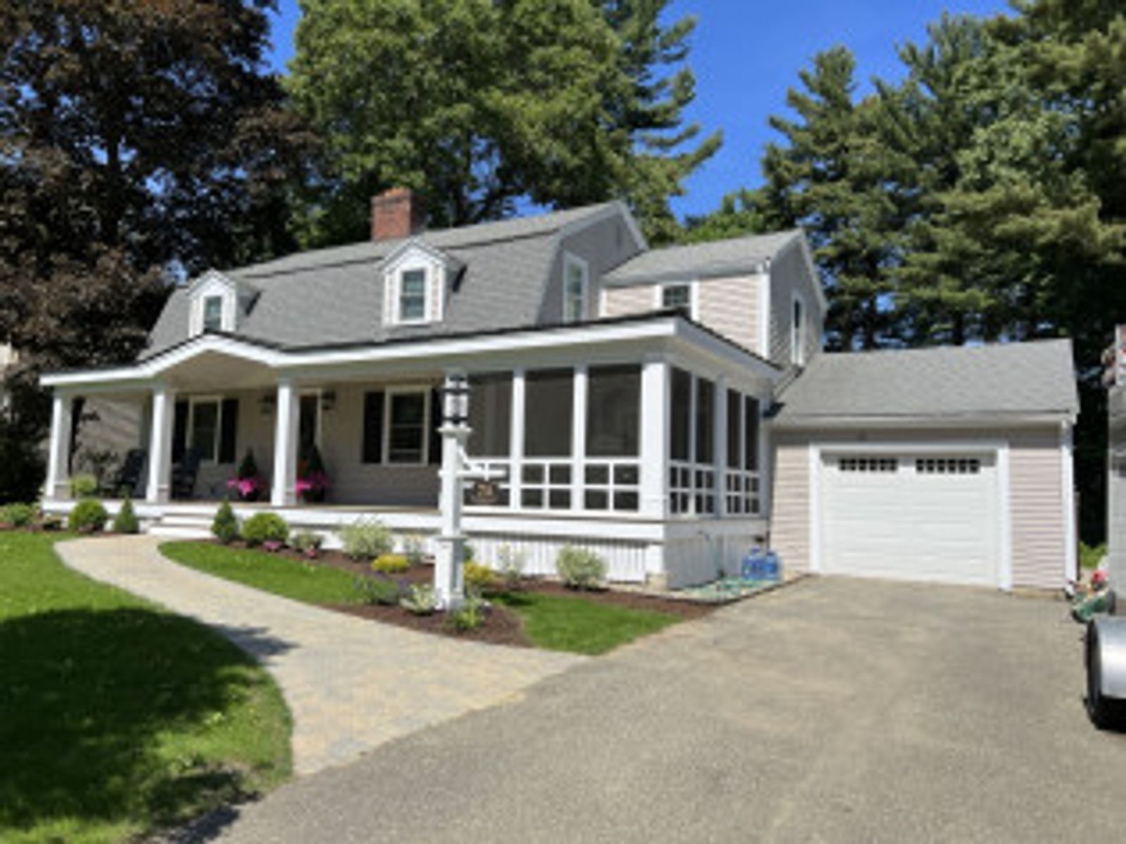 Two-story house with a porch and attached garage; gray siding, asphalt roof, and landscaped yard.