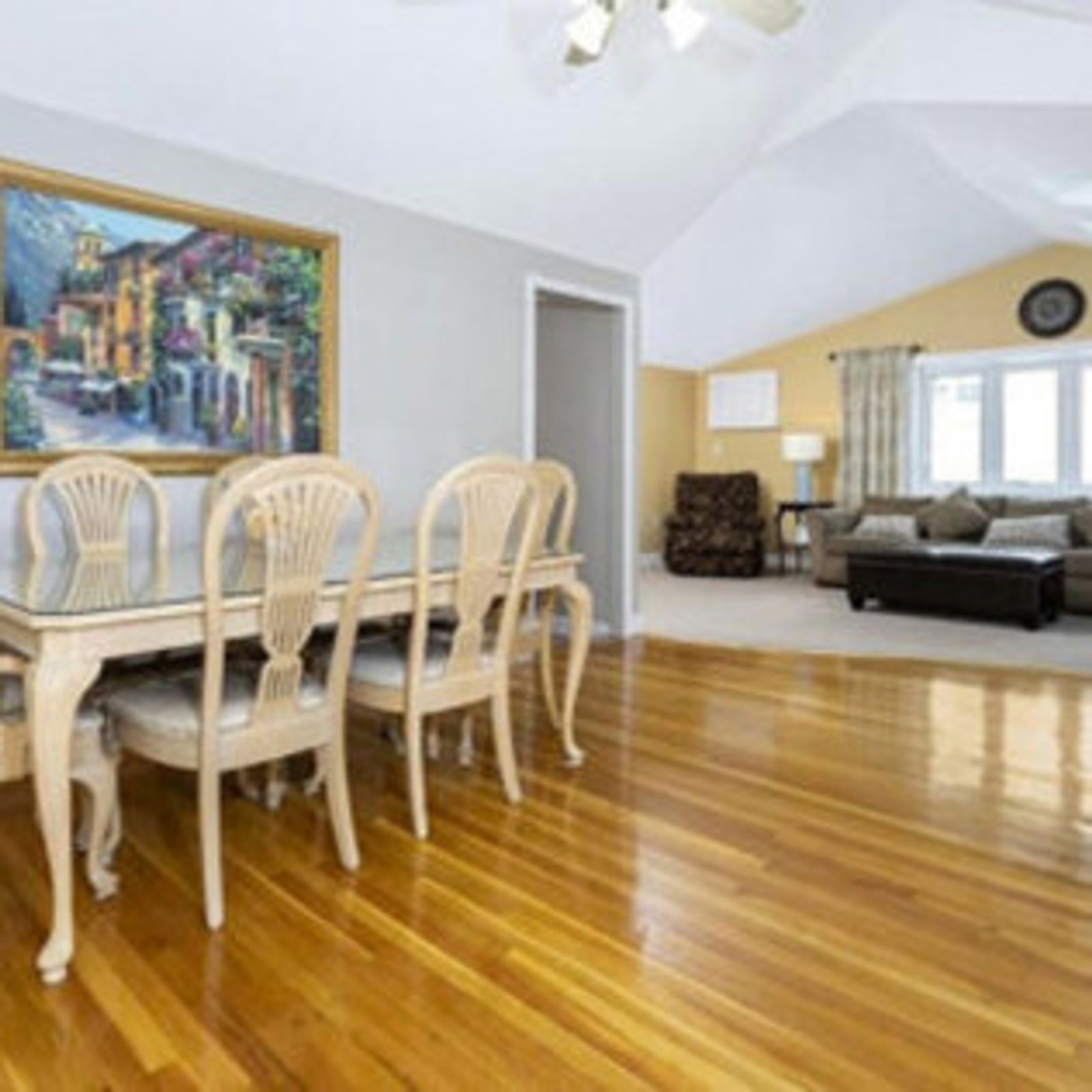 Dining room with a table and chairs, hardwood floors, and a painting on the wall.