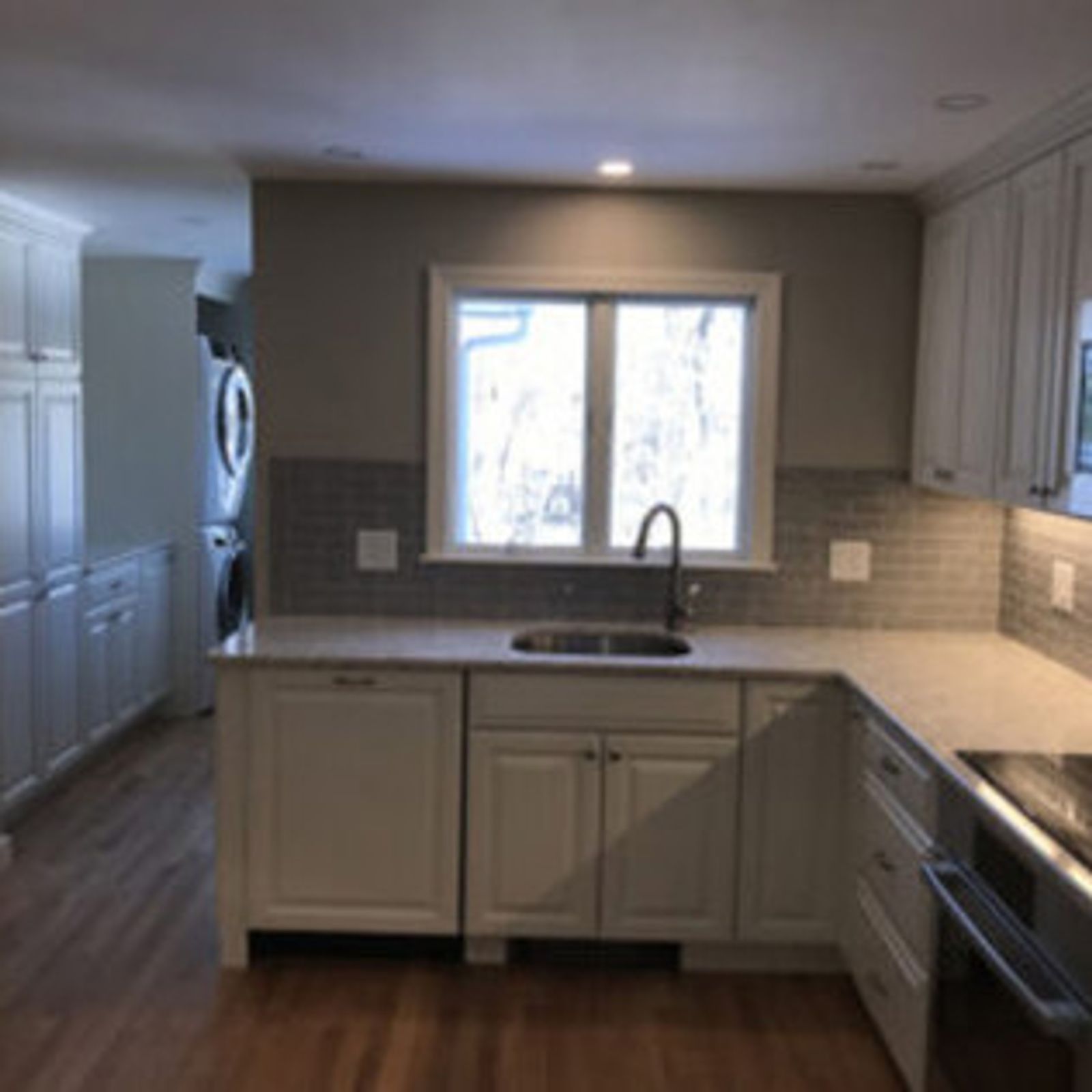 Kitchen with white cabinets, light countertops, and a window above the sink.