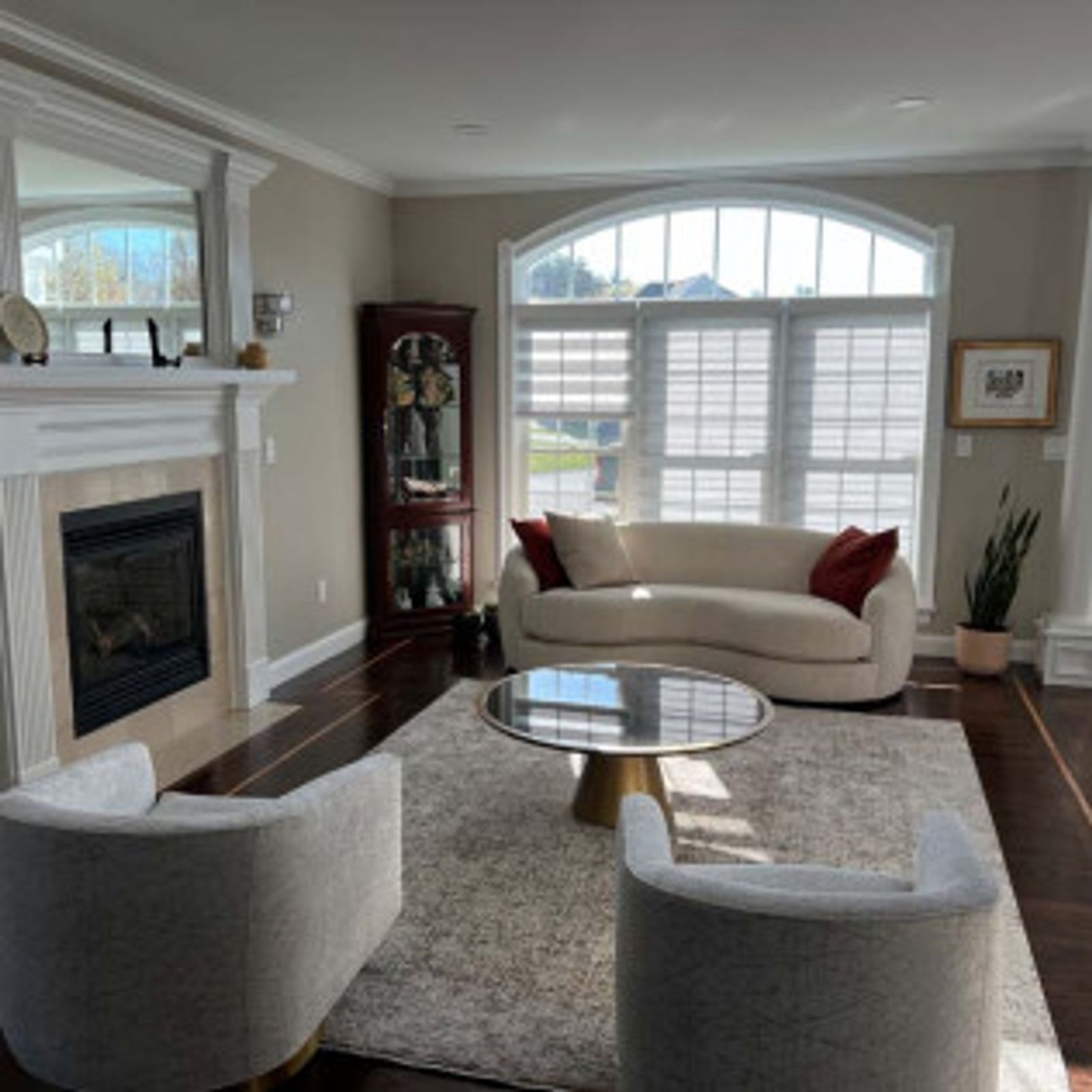 Living room with fireplace, cream sofa, and two armchairs, rug and round coffee table.