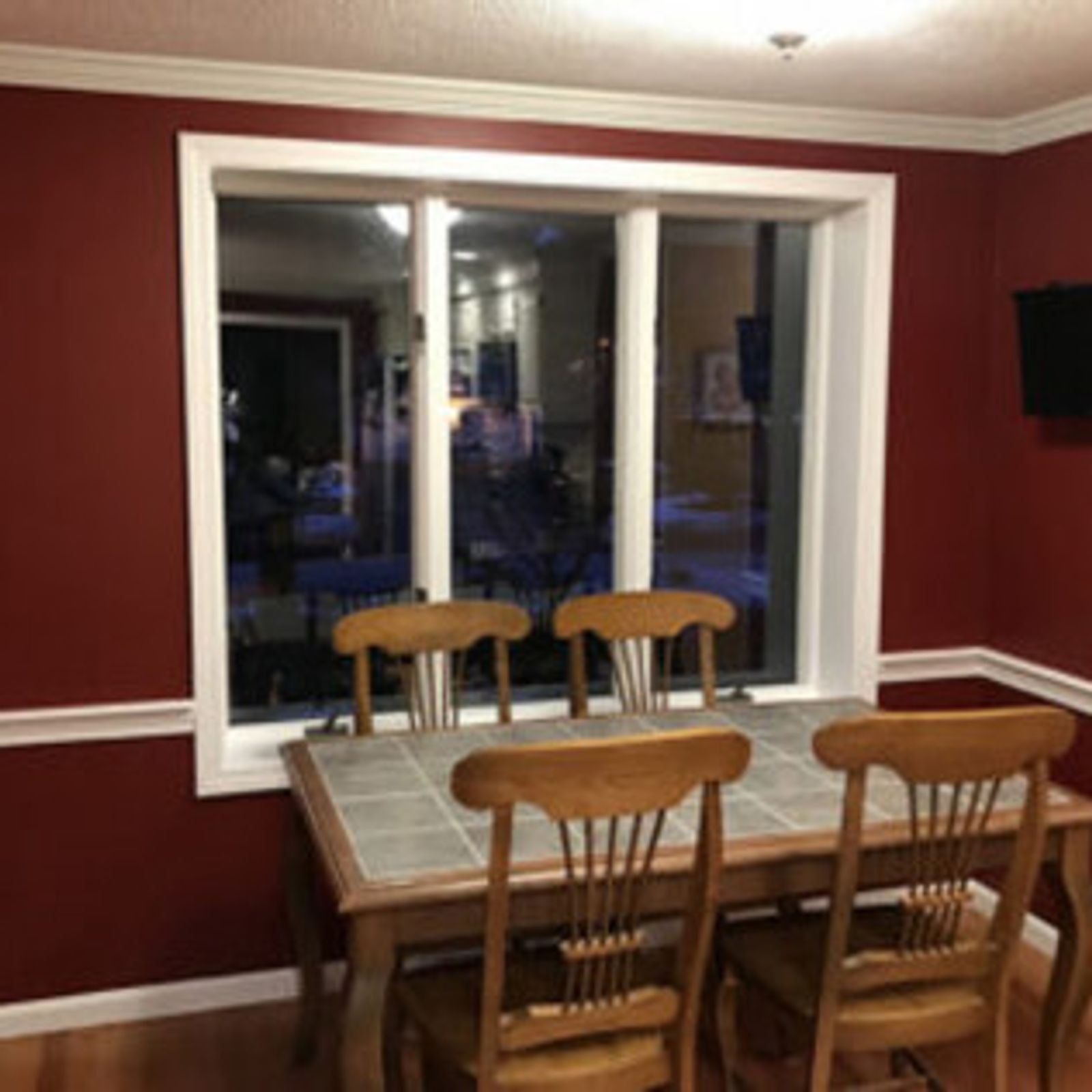 Dining room with a table, chairs, and window. Red walls, white trim.