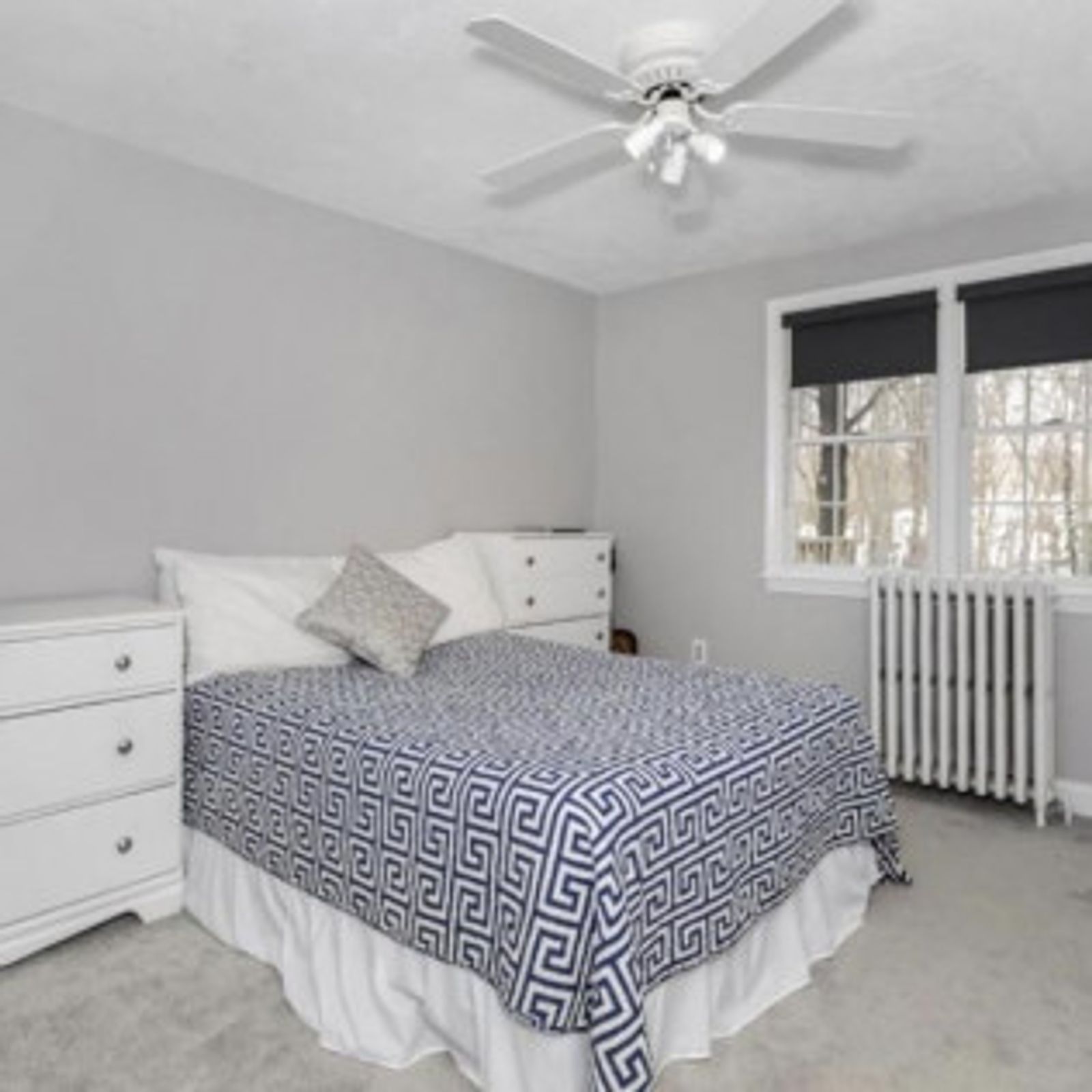 Bedroom with gray walls, white furniture, blue patterned bedspread, and a window.