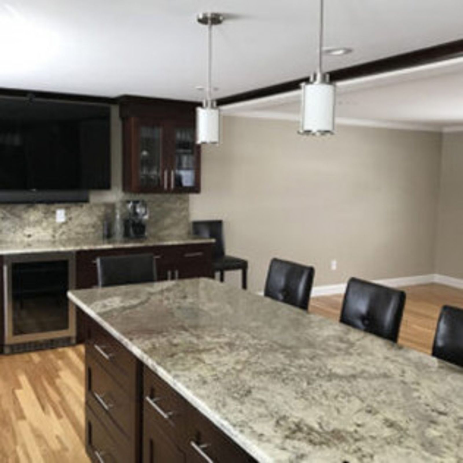 Kitchen with dark cabinetry, granite countertops, and light wood flooring.