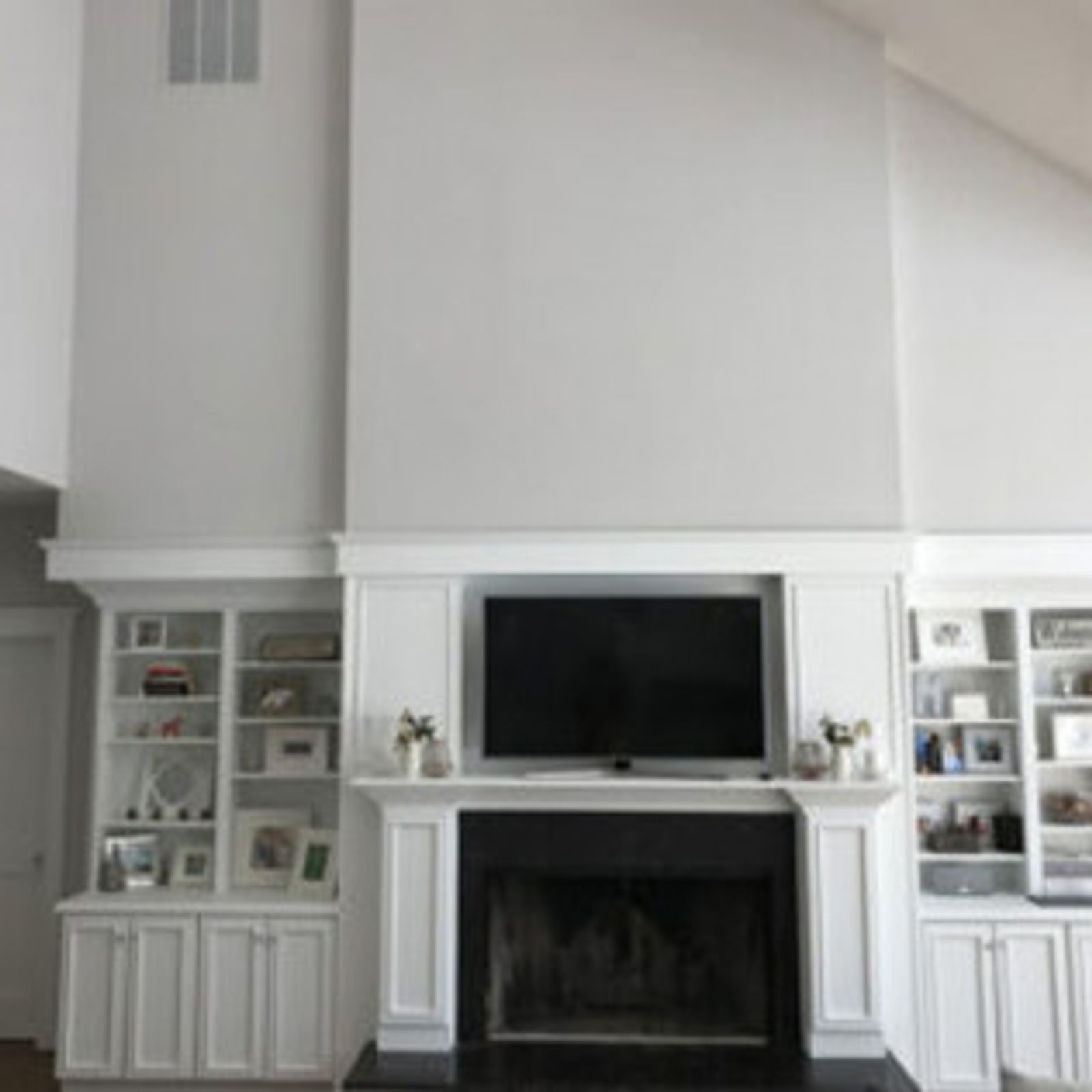 Fireplace with built-in shelves and TV, painted in white and gray, with black fireplace surround.
