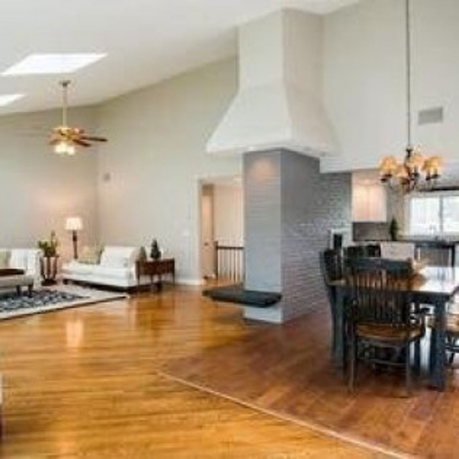 Spacious living room with hardwood floors, a dining area, and a white, angular range hood.
