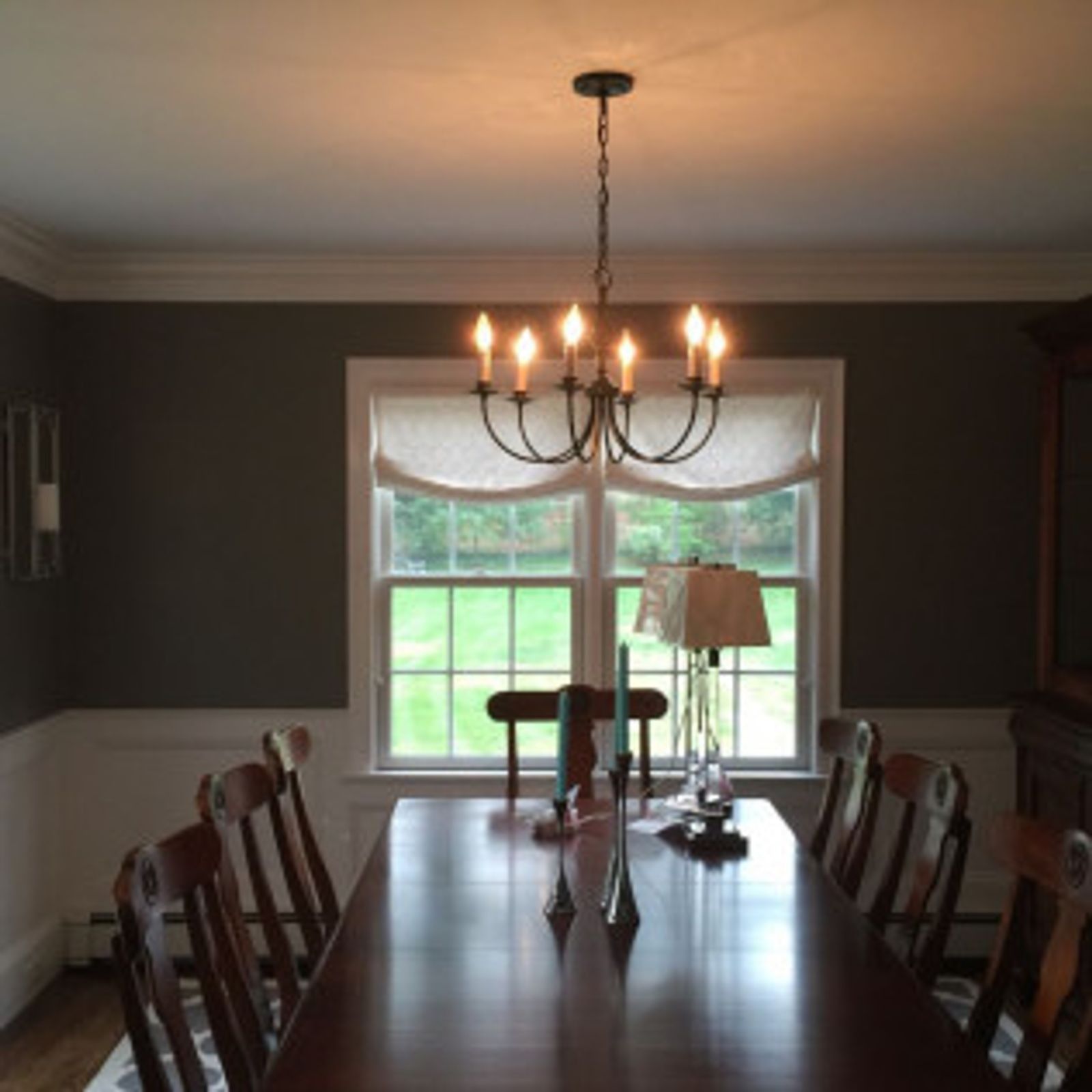 Dining room with dark brown walls, white trim, and a chandelier above a long wooden table.