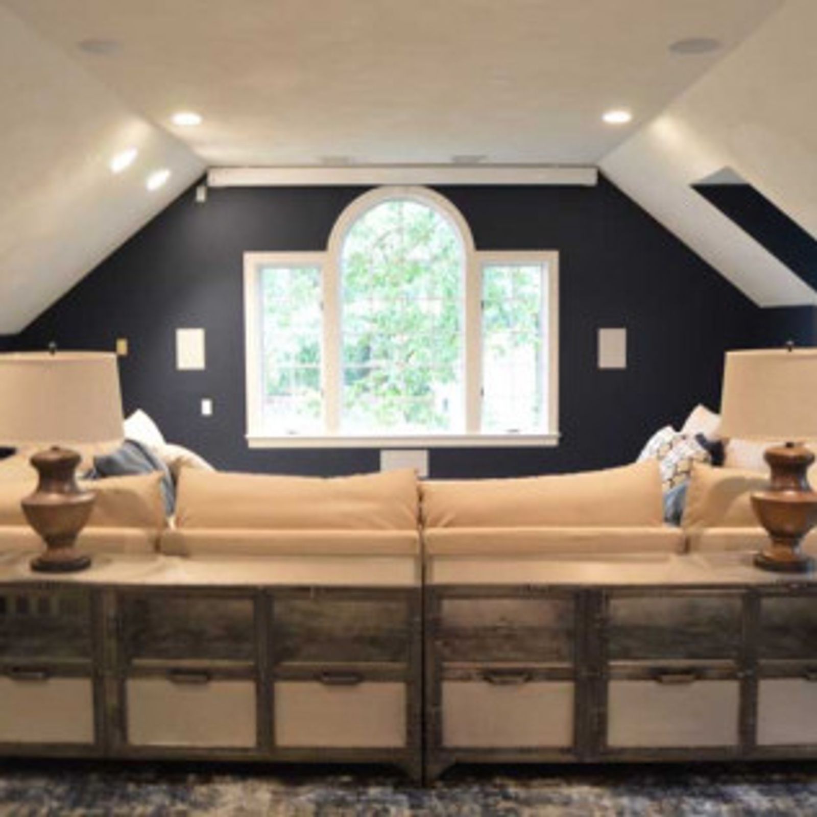 A room with a blue accent wall, neutral sofas, and a large window.