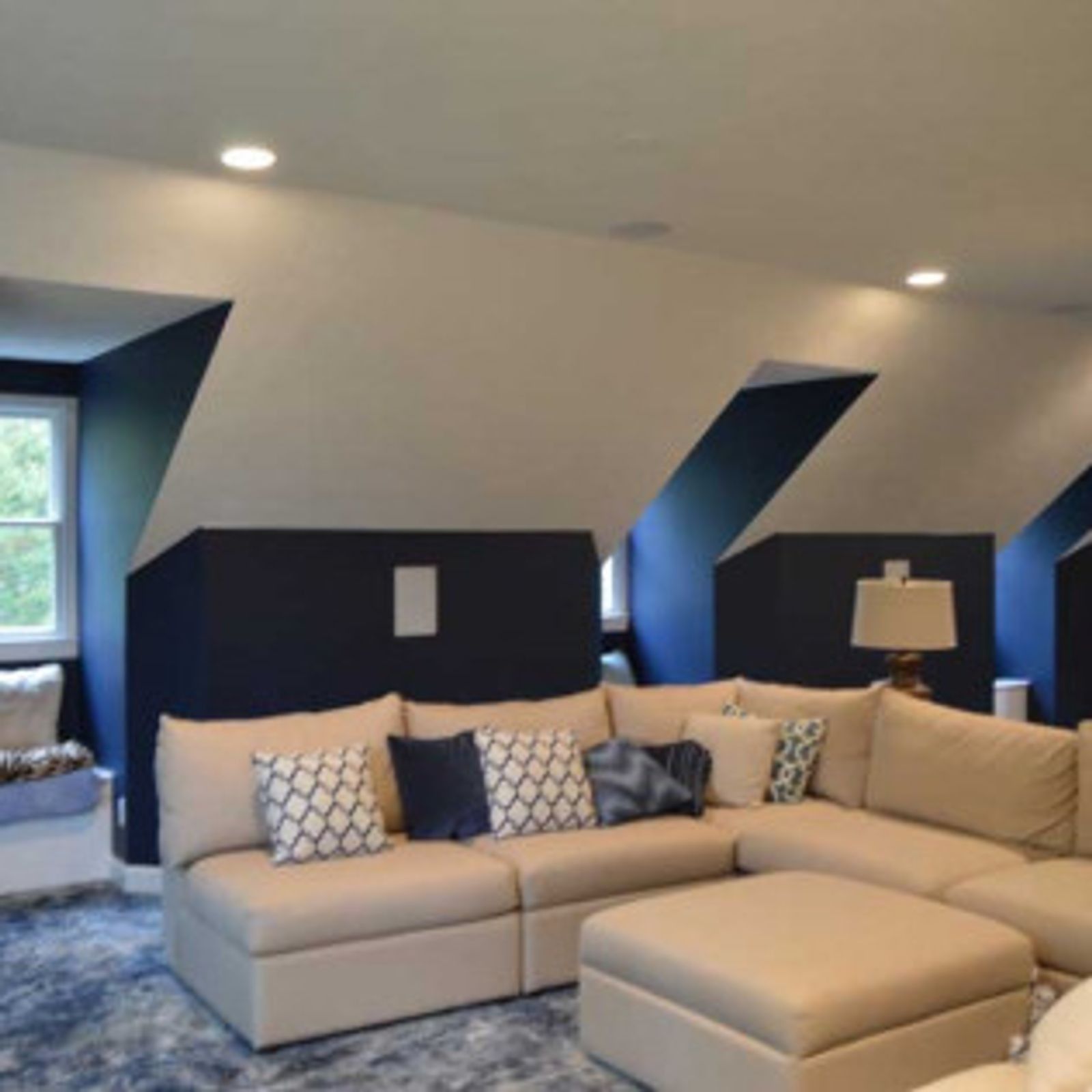Cozy living room with cream sectional sofa, dark blue walls, and angled ceilings.