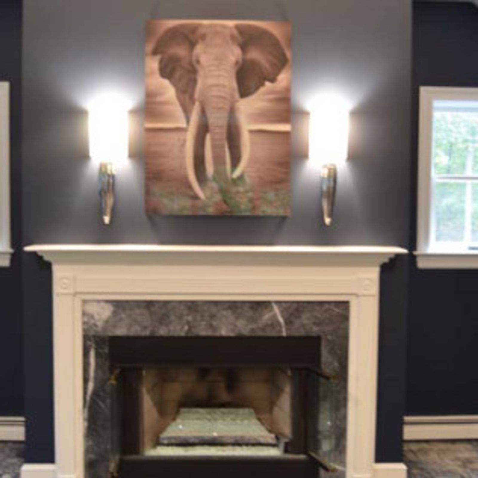 Fireplace with gray marble and an elephant art piece, flanked by wall sconces on a dark blue wall.