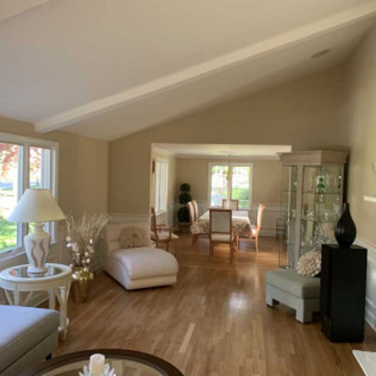 Living room with chaise lounge, dining area, hardwood floors, and tan walls.