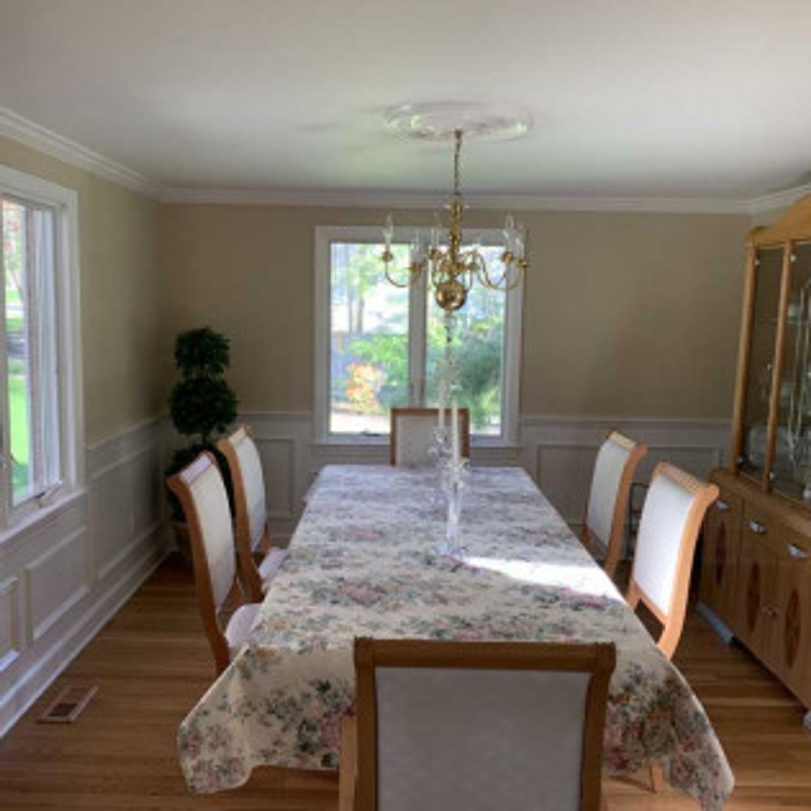 Dining room with a long table set with chairs, a china cabinet, and a chandelier.