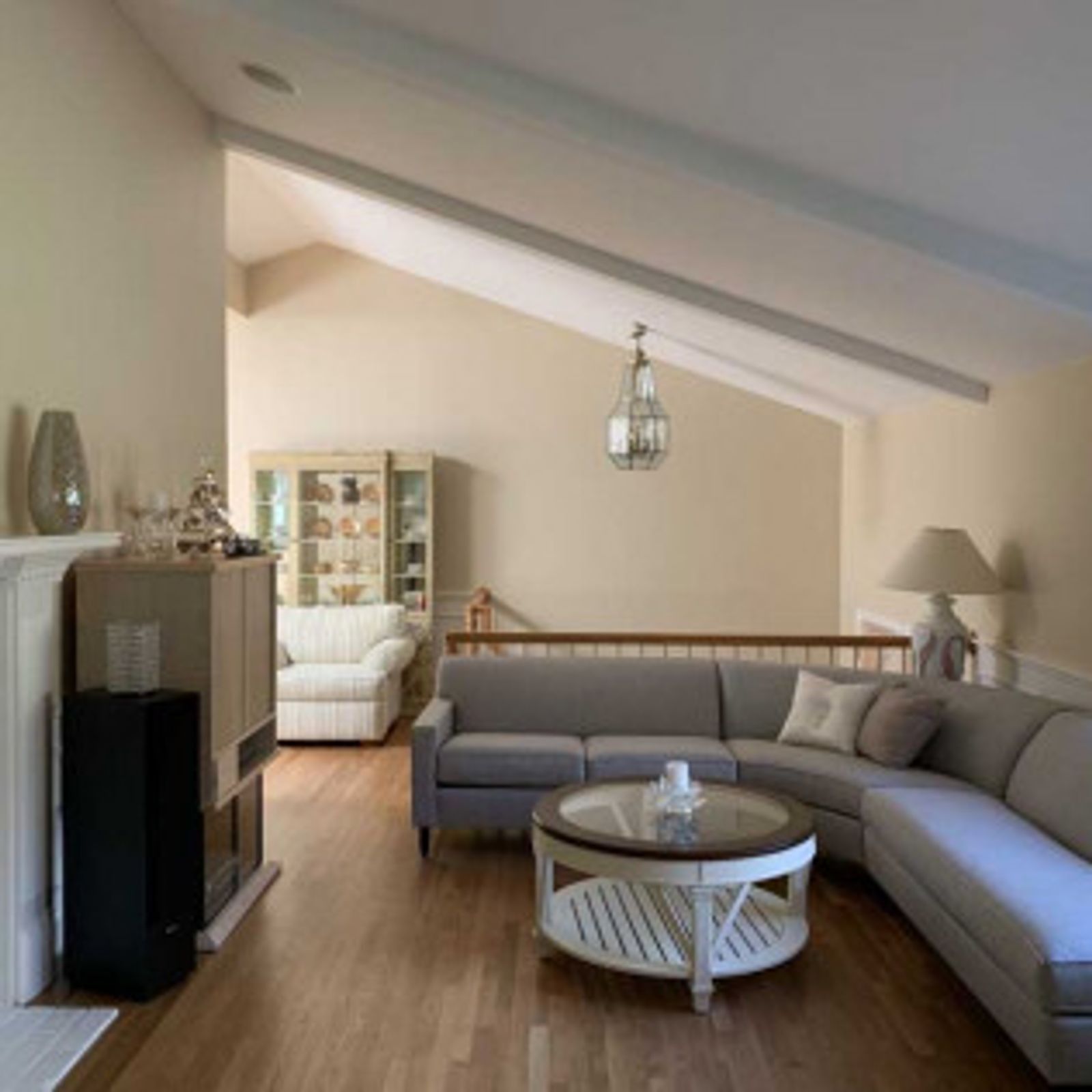 Living room with neutral walls, a gray sectional, and a round coffee table.
