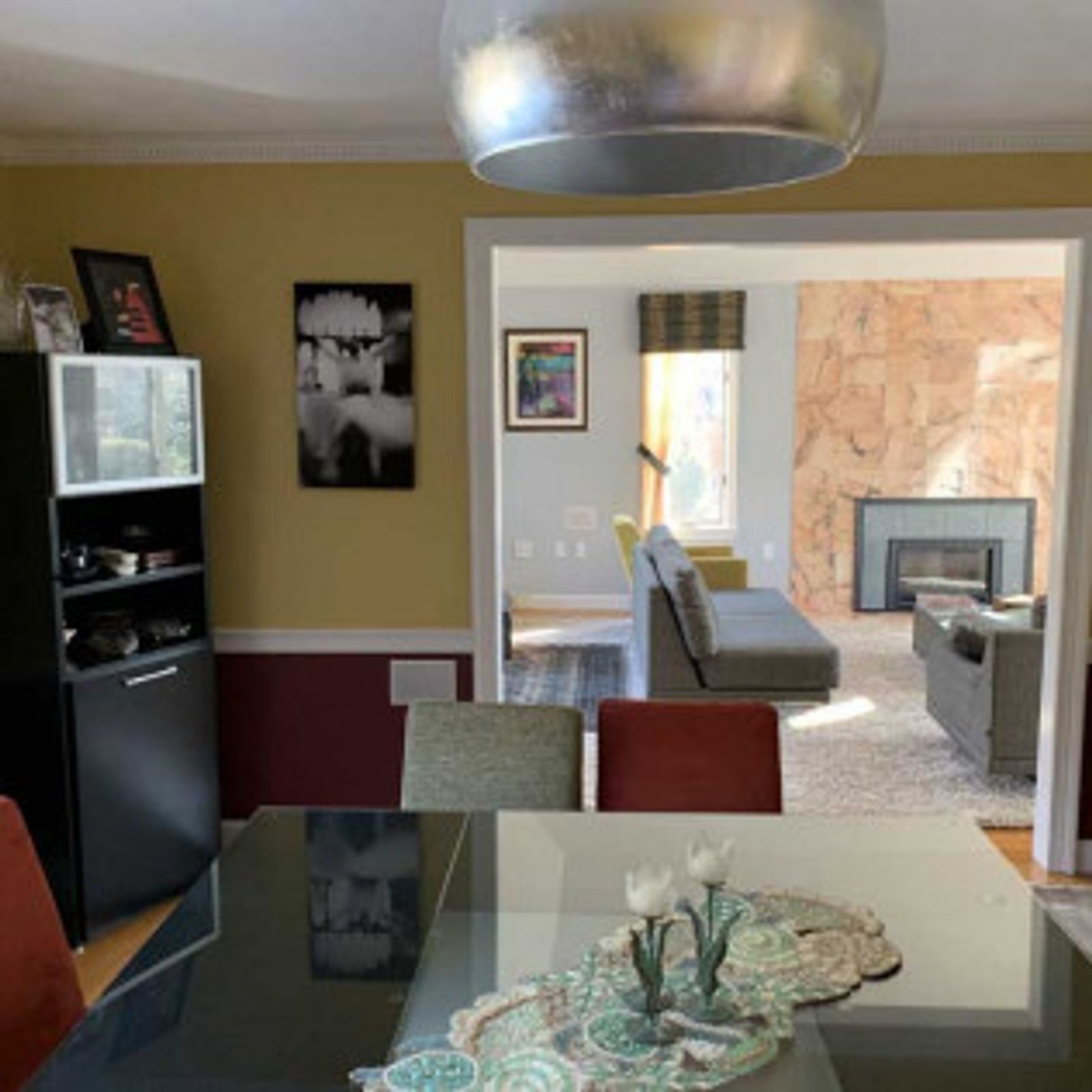 Dining room with table set for meal. Adjacent living room with fireplace and gray sofa.