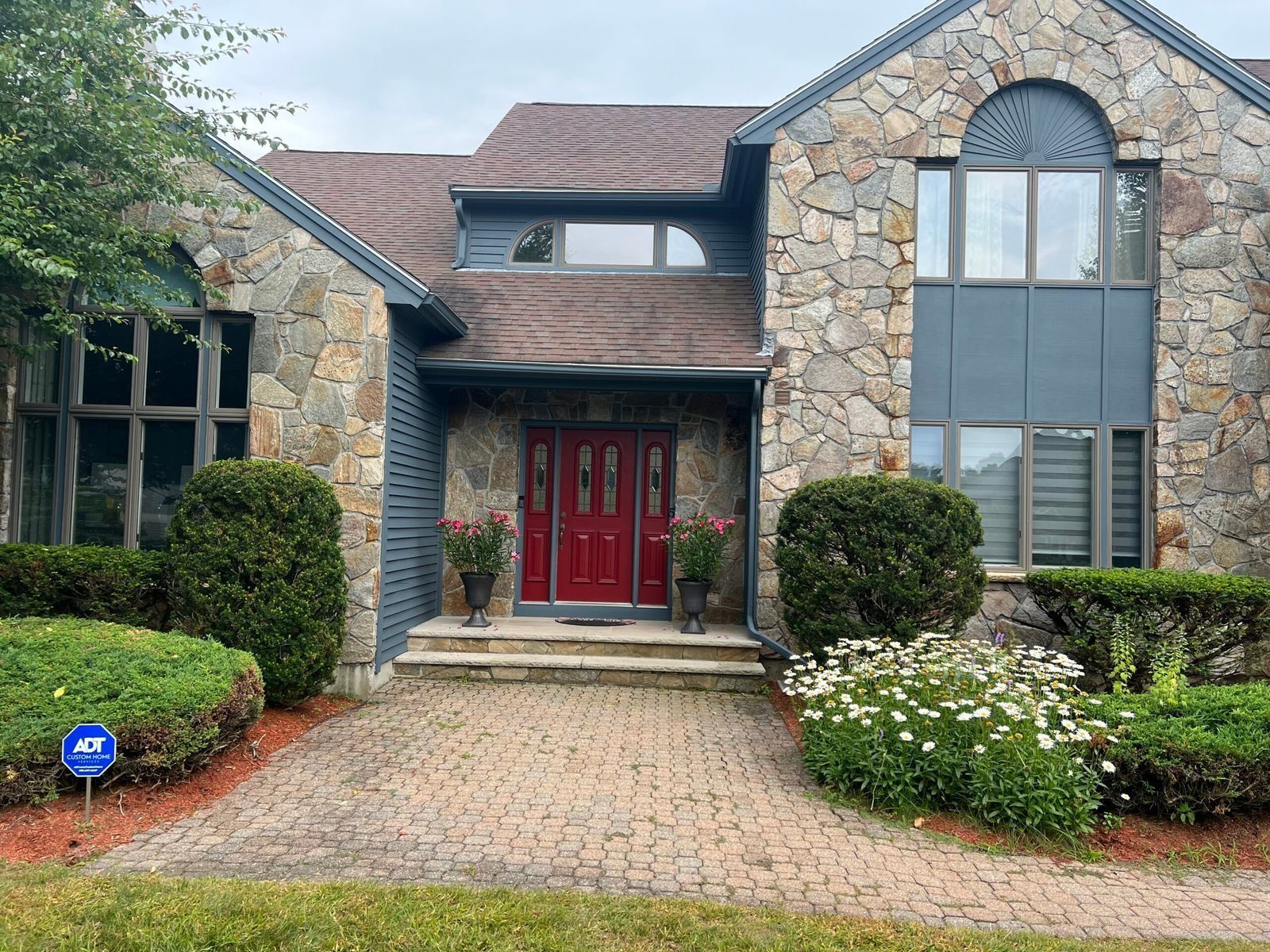 Stone facade house with red front door and brick walkway.