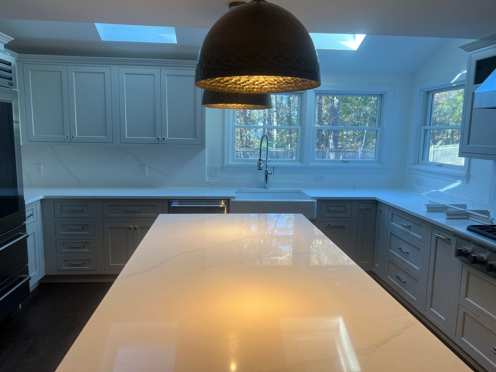 Modern kitchen with white cabinets, island, and large pendant lights.
