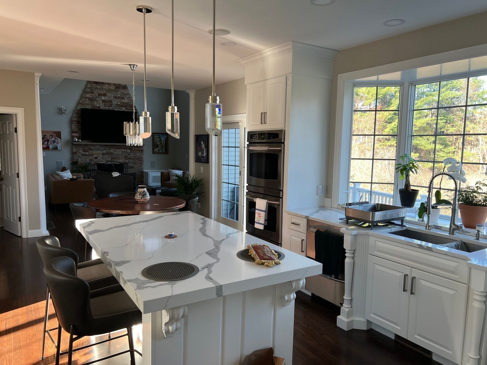 Modern kitchen with white cabinets, island, and window overlooking a sunny outdoor view.