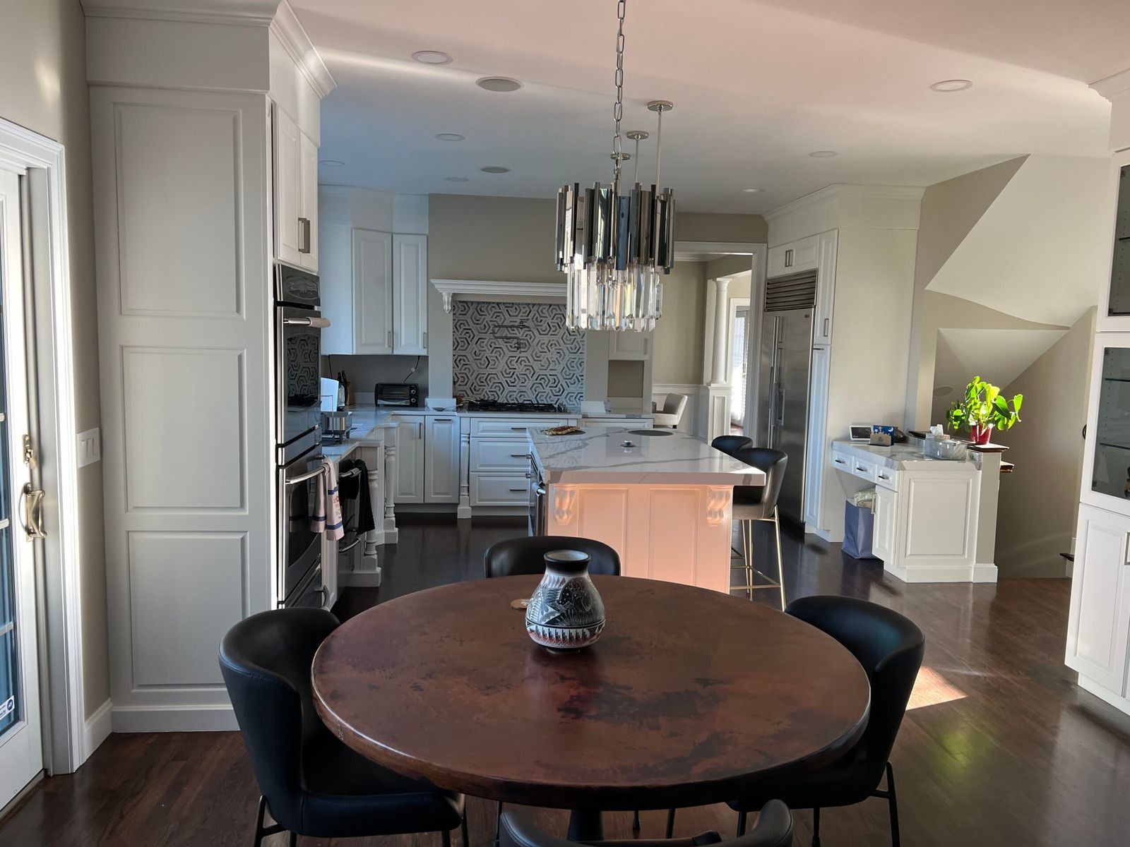 Kitchen with round table, chairs, and pendant light; white cabinets, island, and appliances.