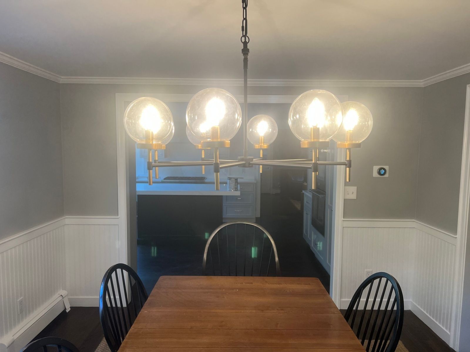 Dining room with a wooden table, black chairs, and a modern chandelier.