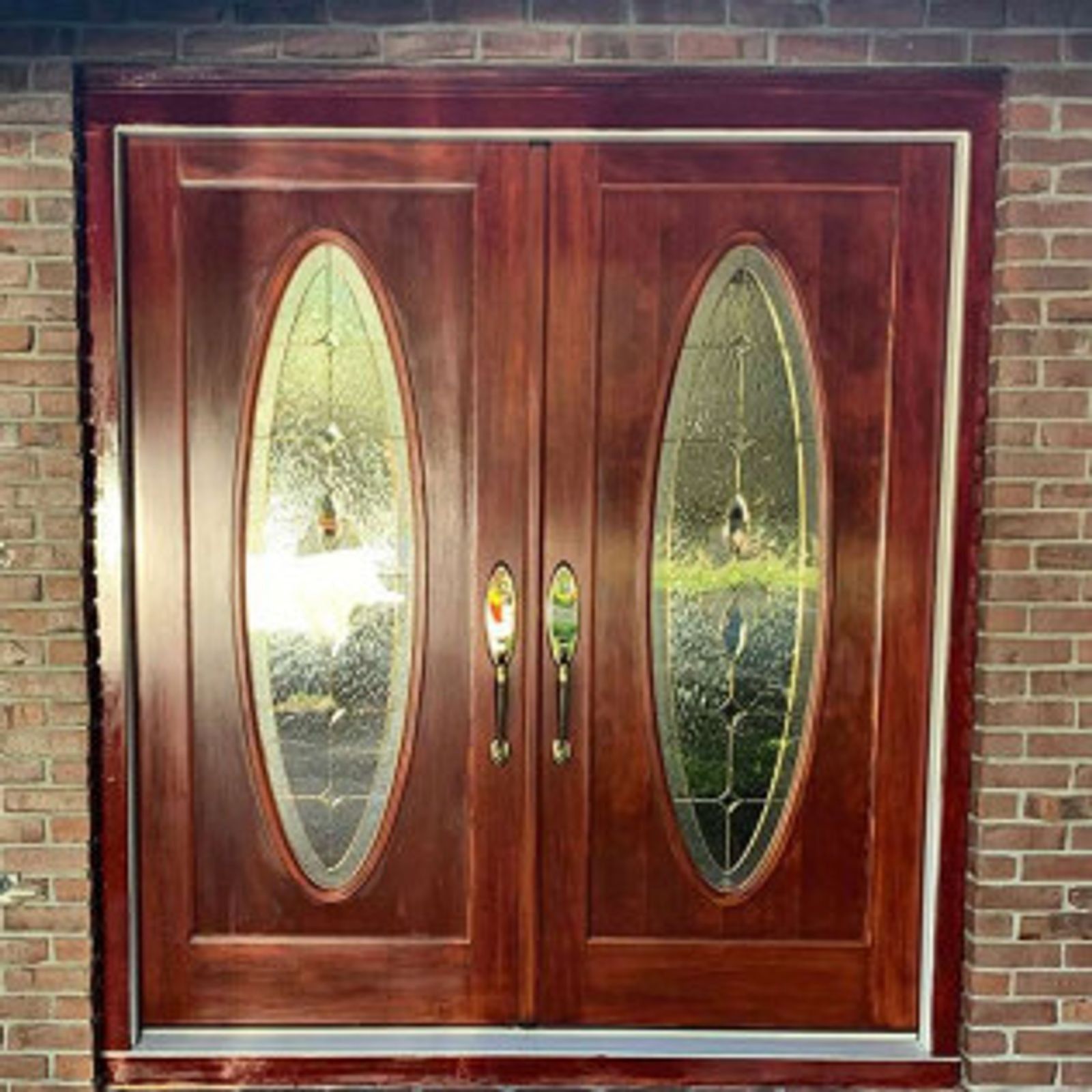 Double wooden front doors with oval glass panels and red brick exterior.