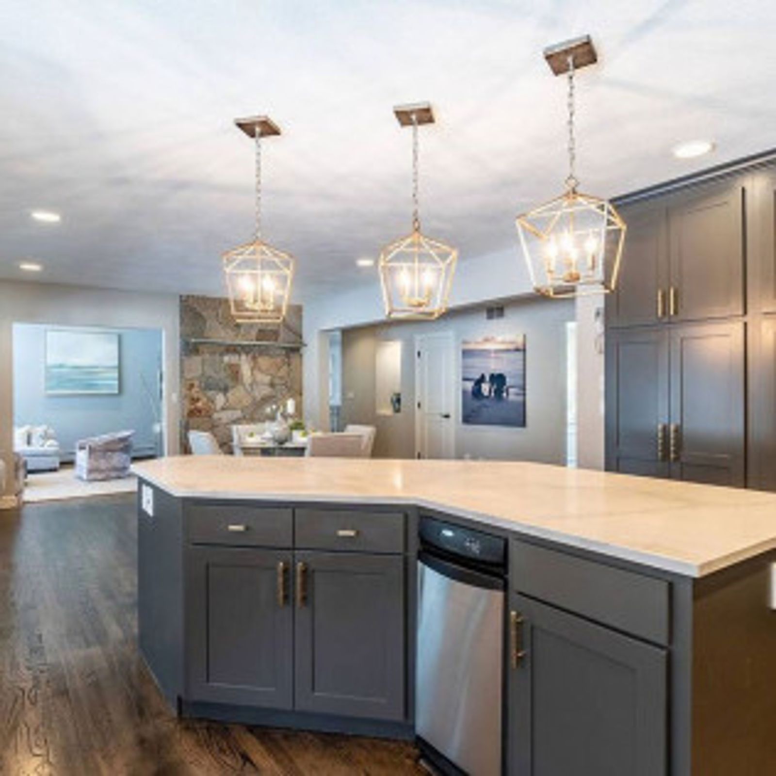 Modern kitchen with gray cabinets, white countertop, stainless steel appliances, and gold pendant lights.