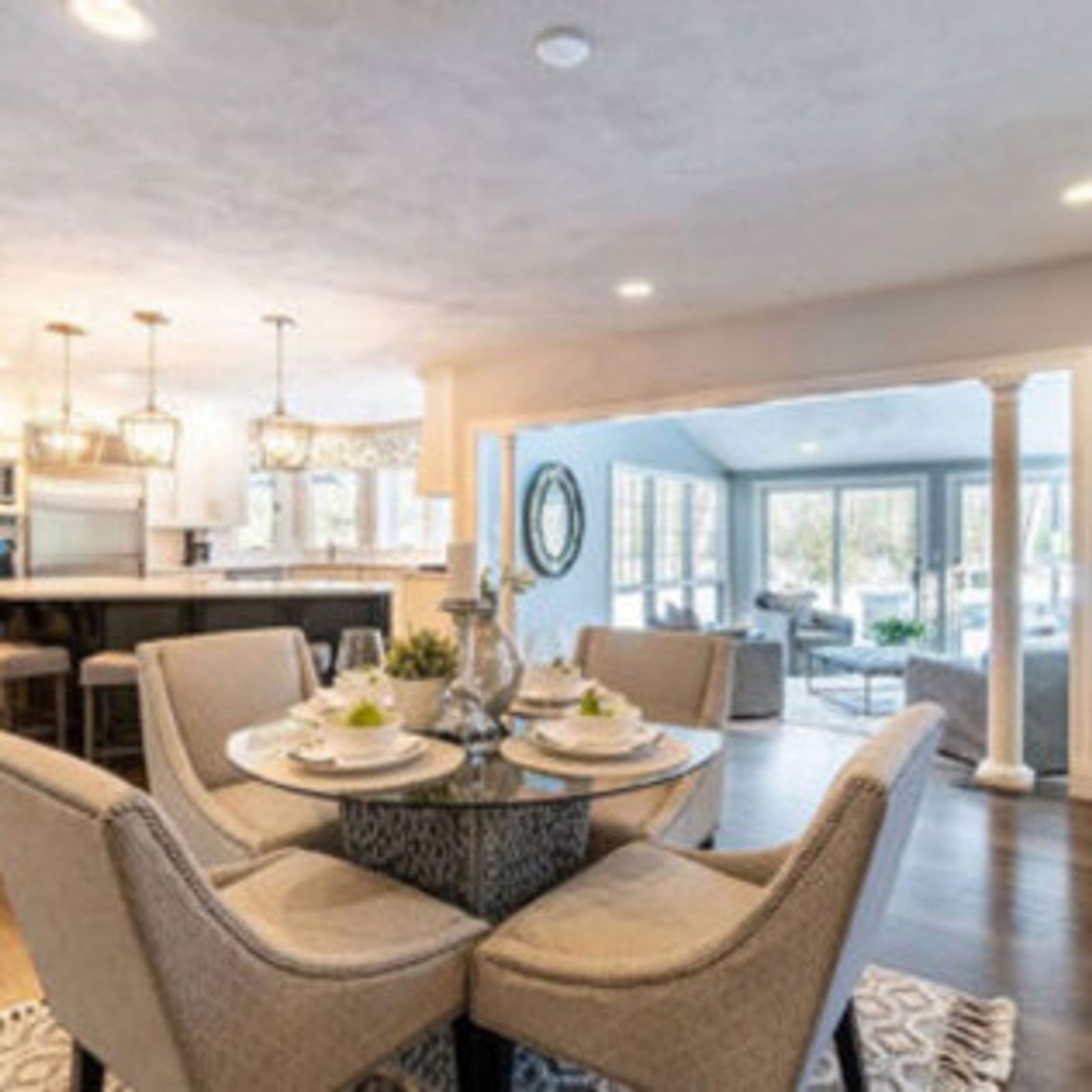 Dining room with round table, four chairs, and open view to living room.