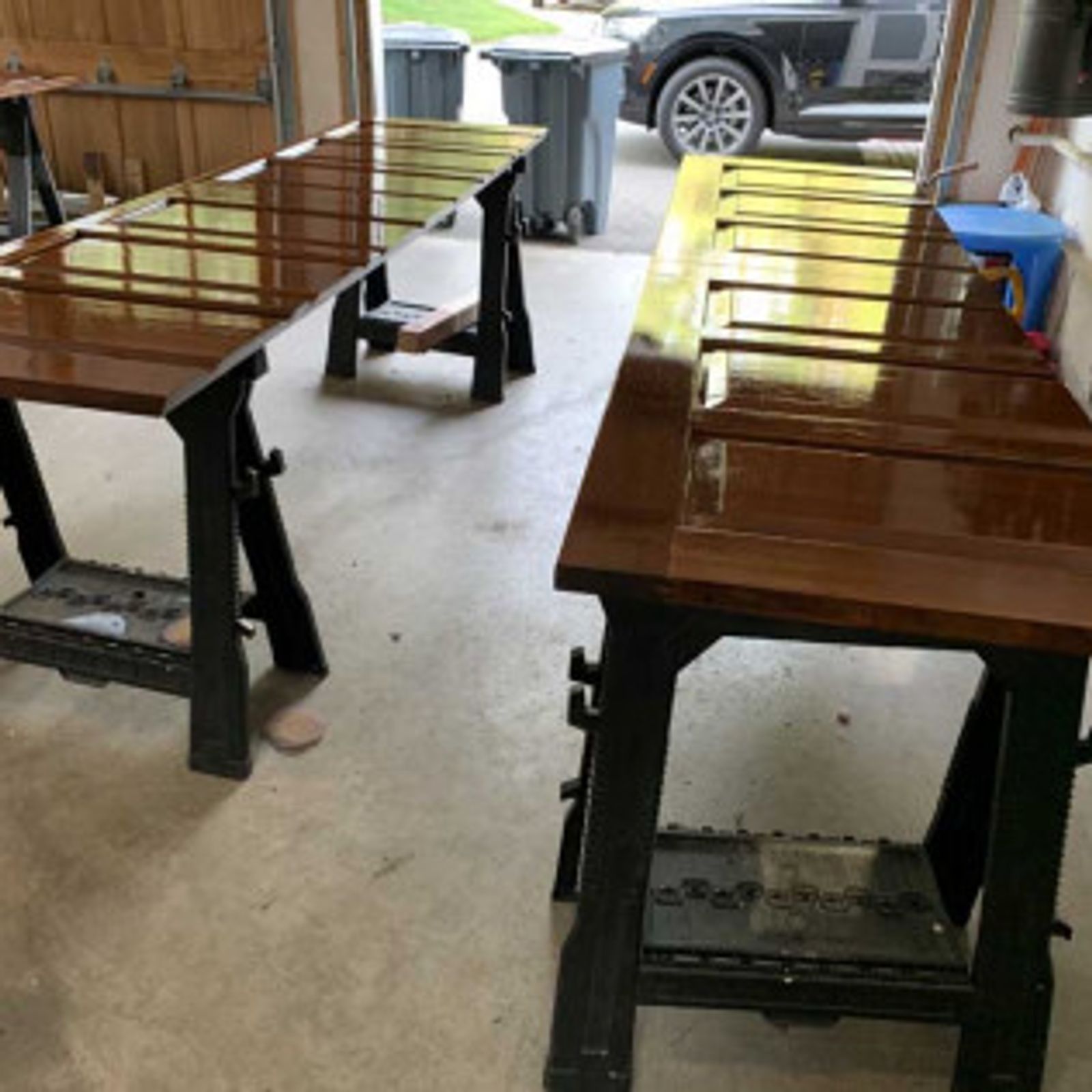 Two stained wood doors on black sawhorses, indoors with a garage door visible.