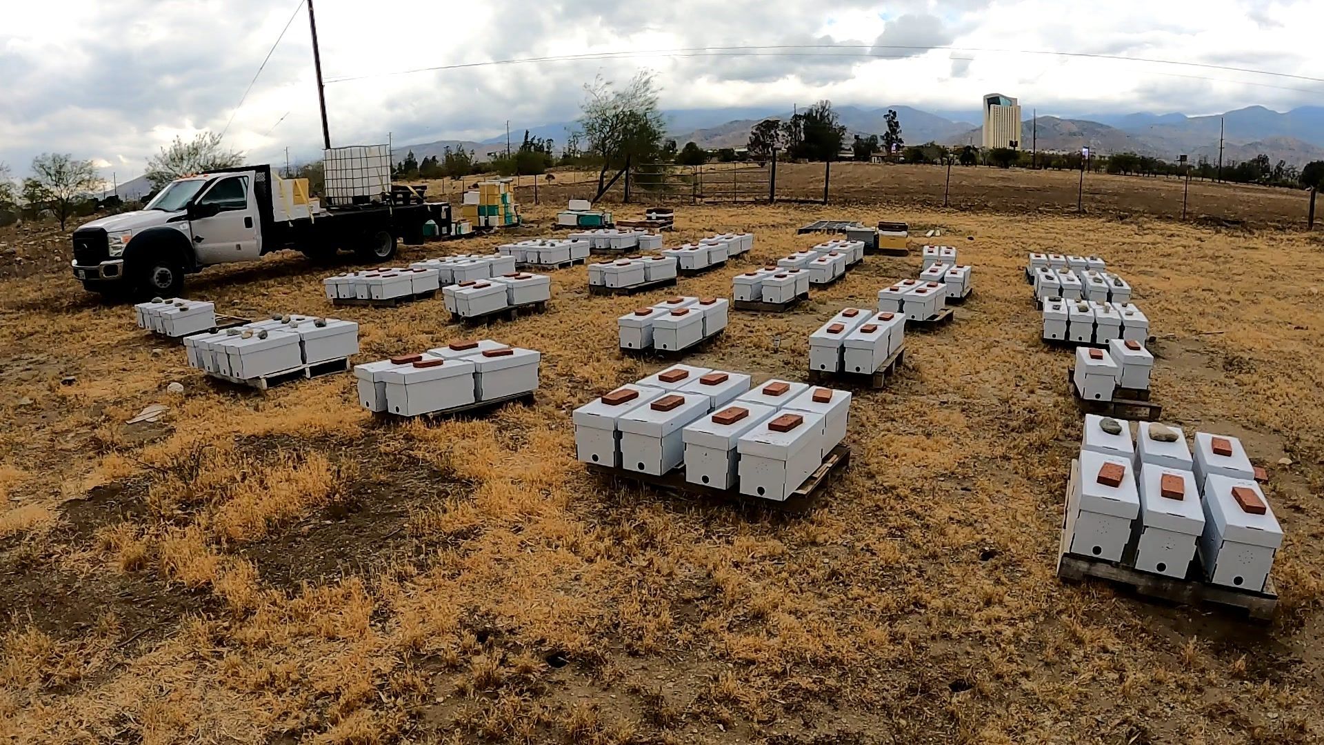 Batteries laid out on dirt field, with truck in the background. Mountain and tower are visible.