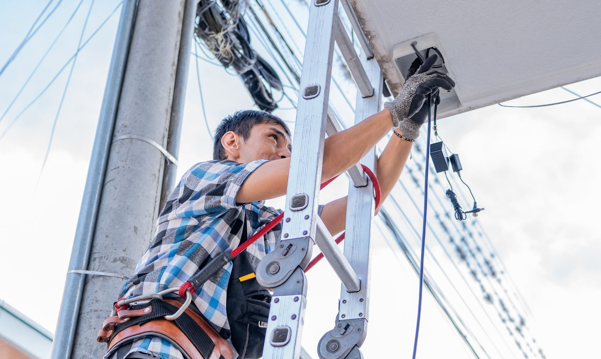 A technician on a ladder mounting a professional security camera