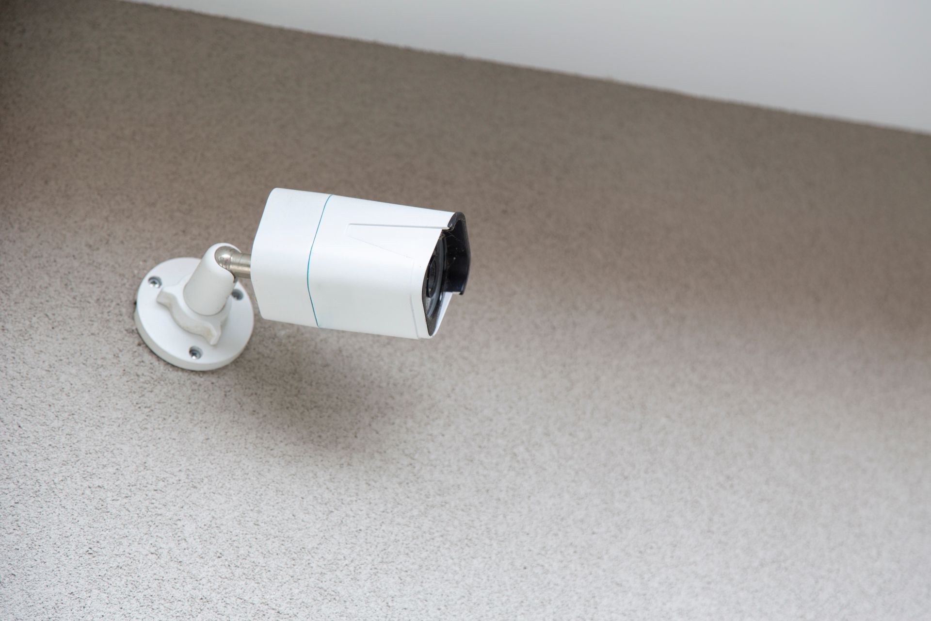 A home security camera installed on a beige wall.