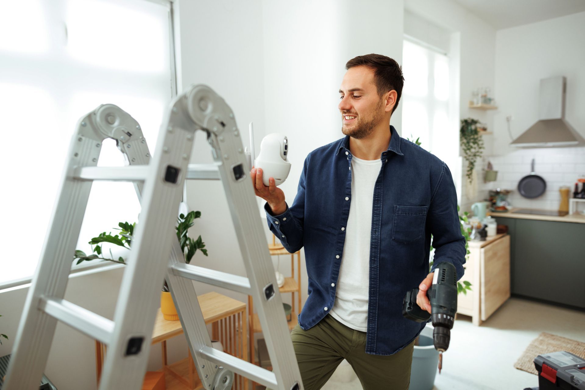 Young man installing security camera at home, showcasing his skills as a security system installer.