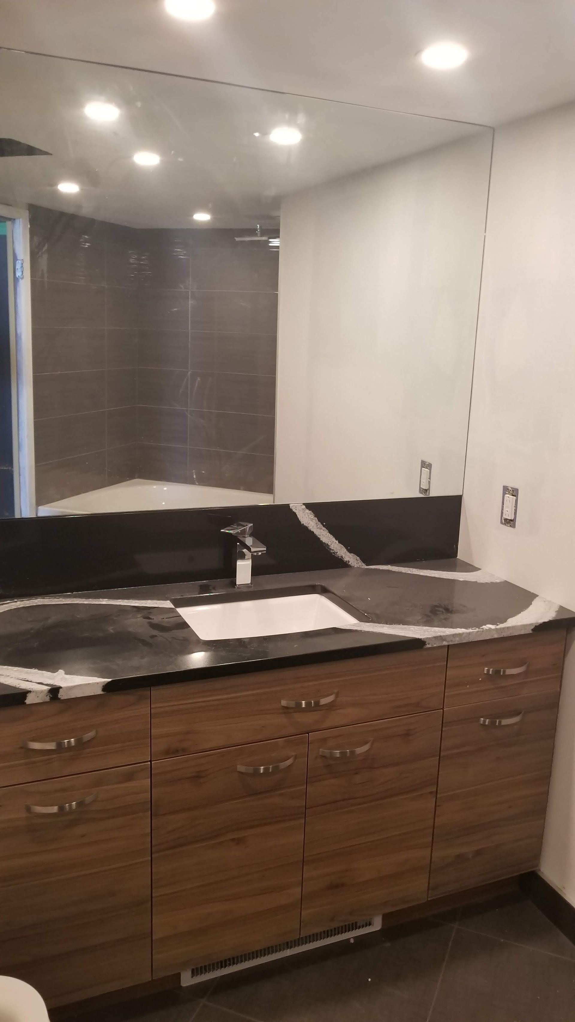 Une salle de bain avec un grand miroir et des armoires en bois.