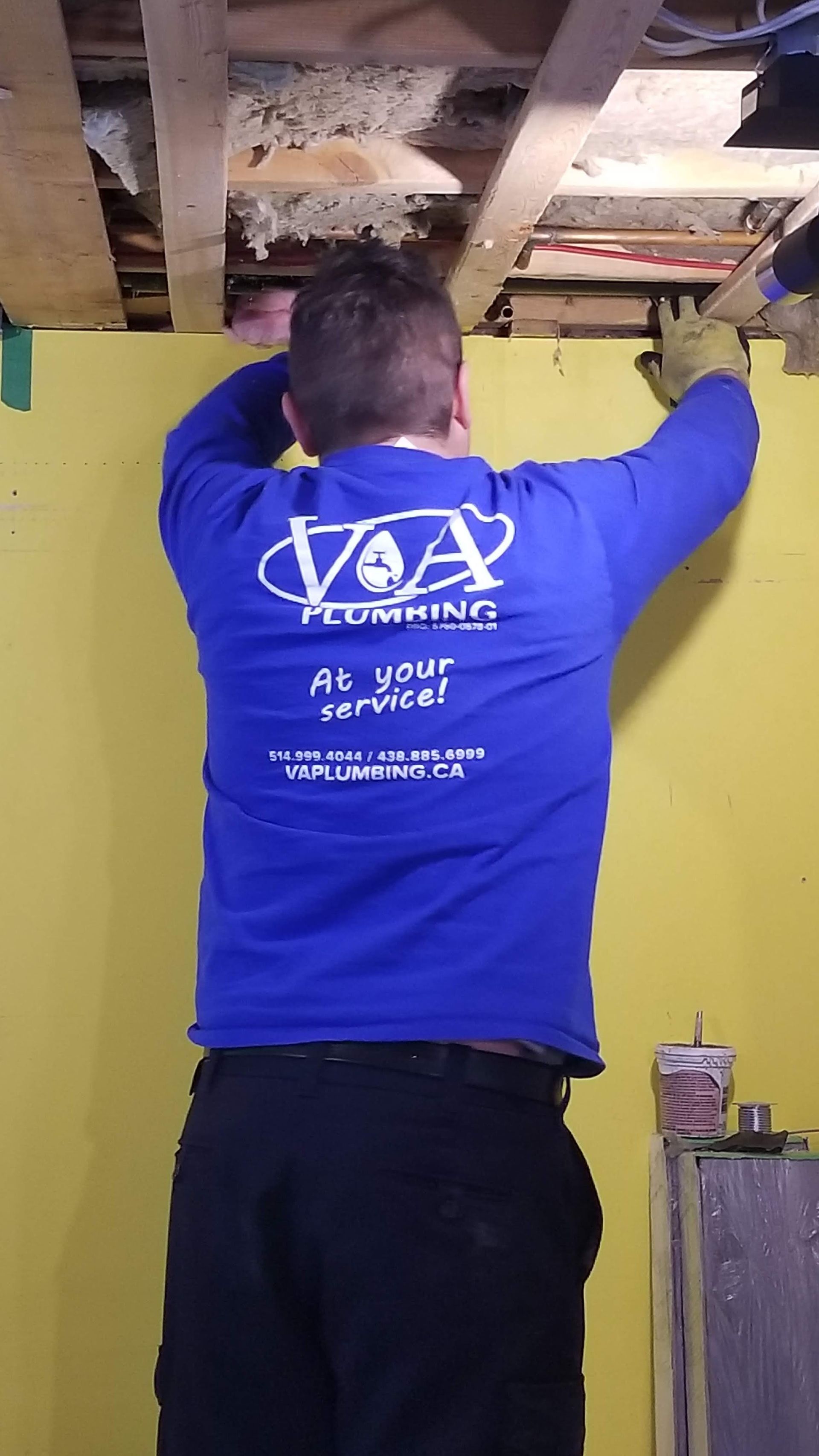 Un homme en chemise bleue travaille sous un plafond.