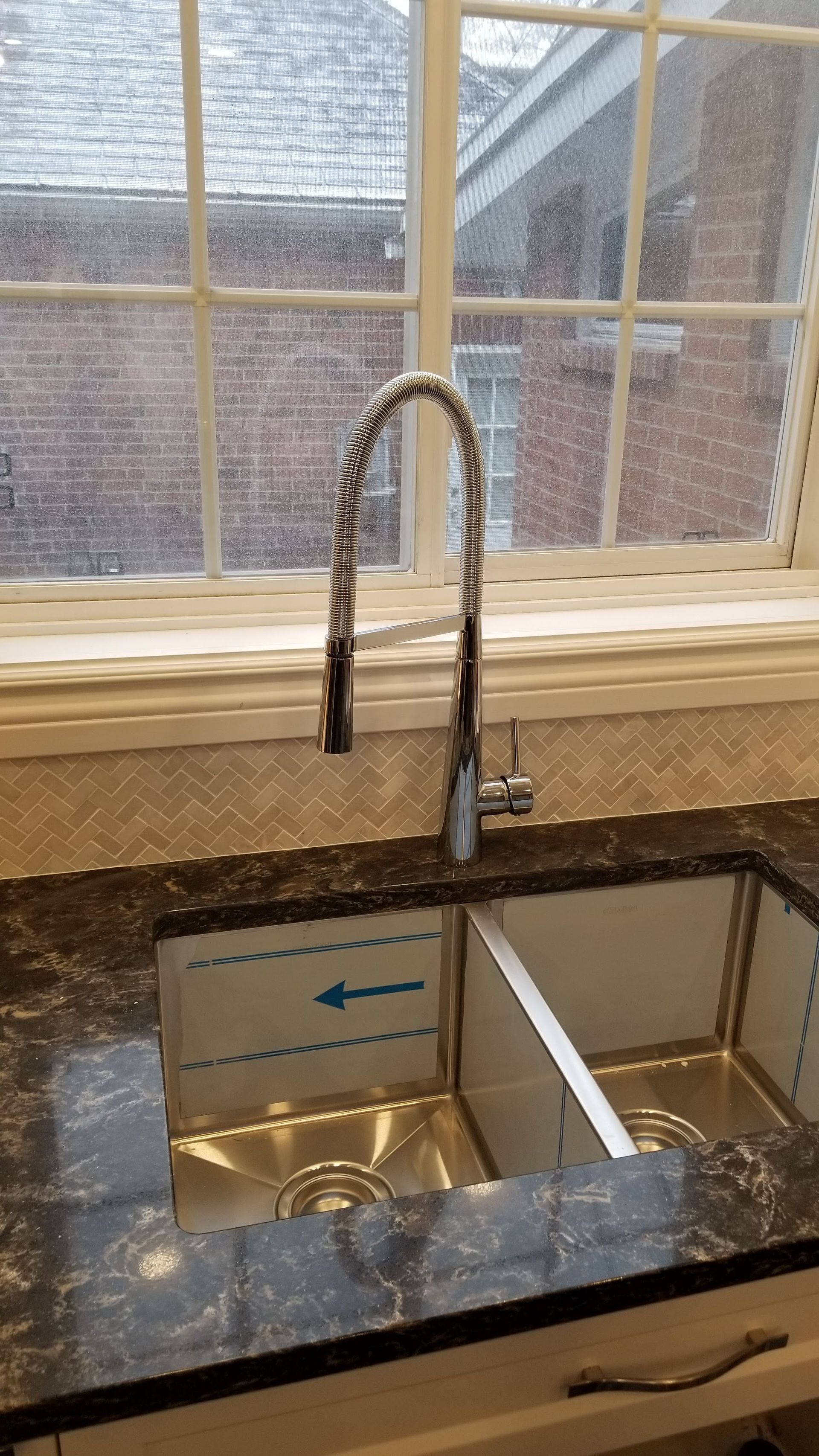 Un évier de cuisine avec un robinet et une fenêtre en arrière-plan.