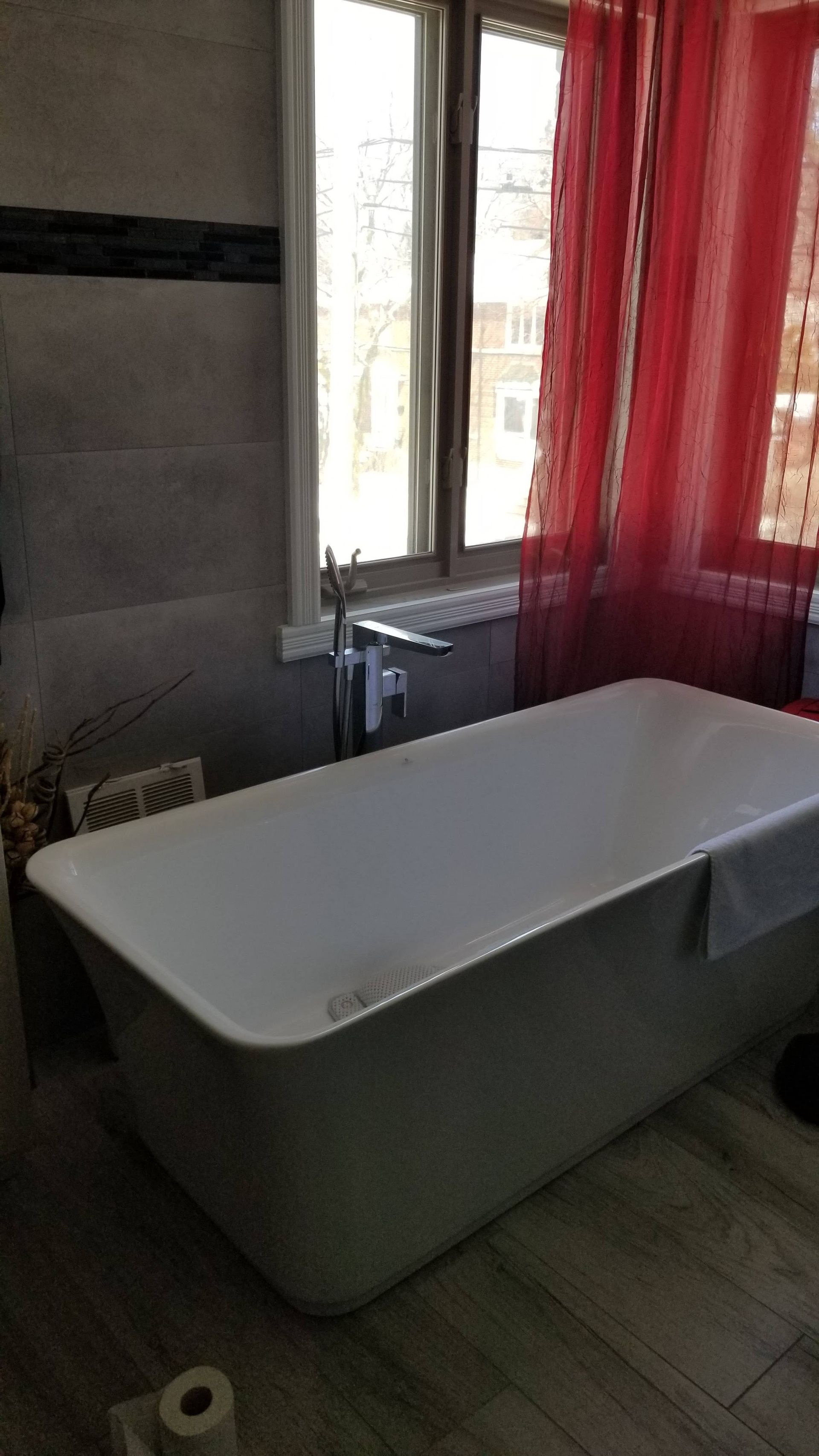 Une baignoire est placée dans une salle de bain à côté d'une fenêtre.