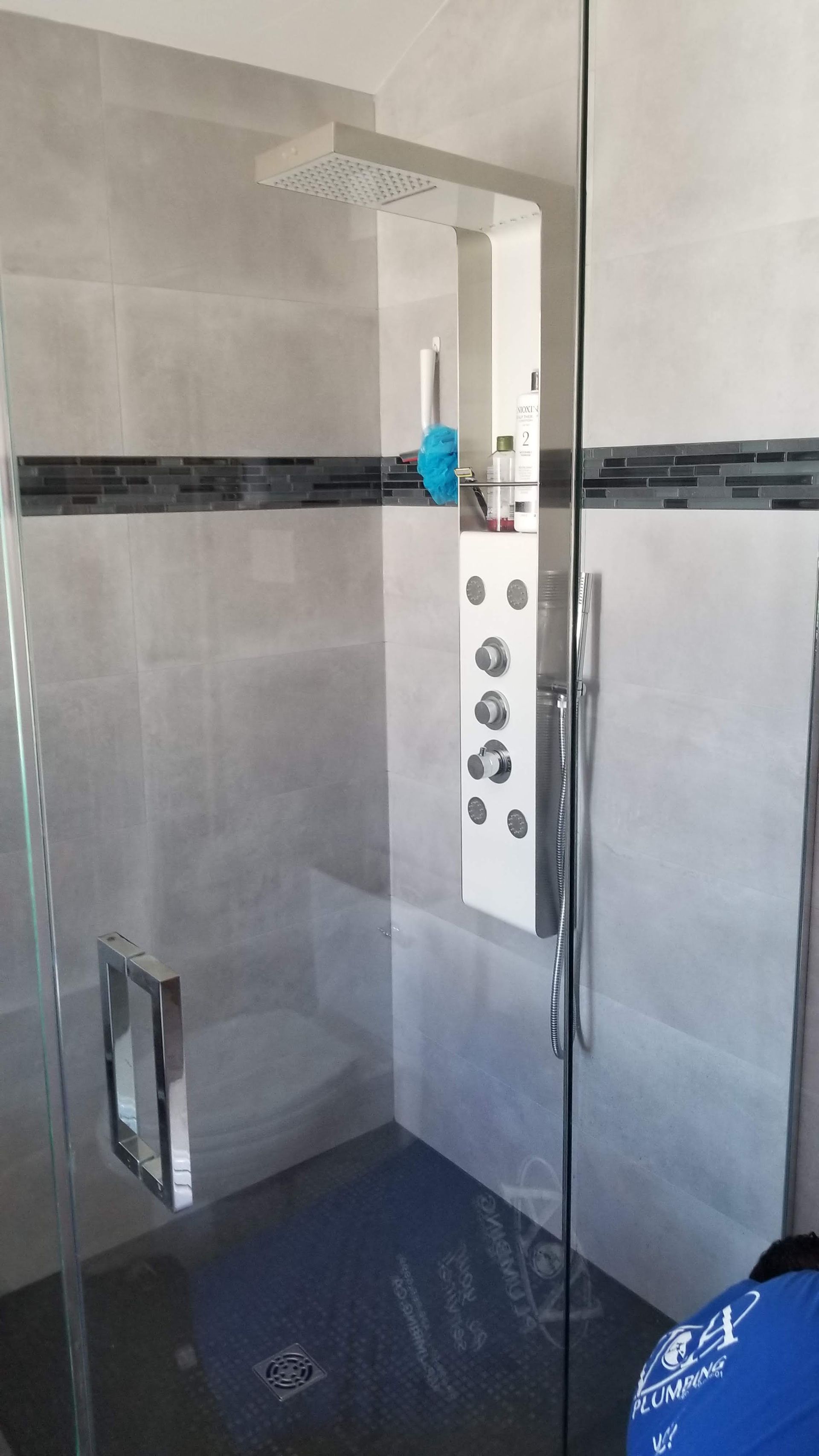 Une cabine de douche avec une porte vitrée et une pomme de douche.