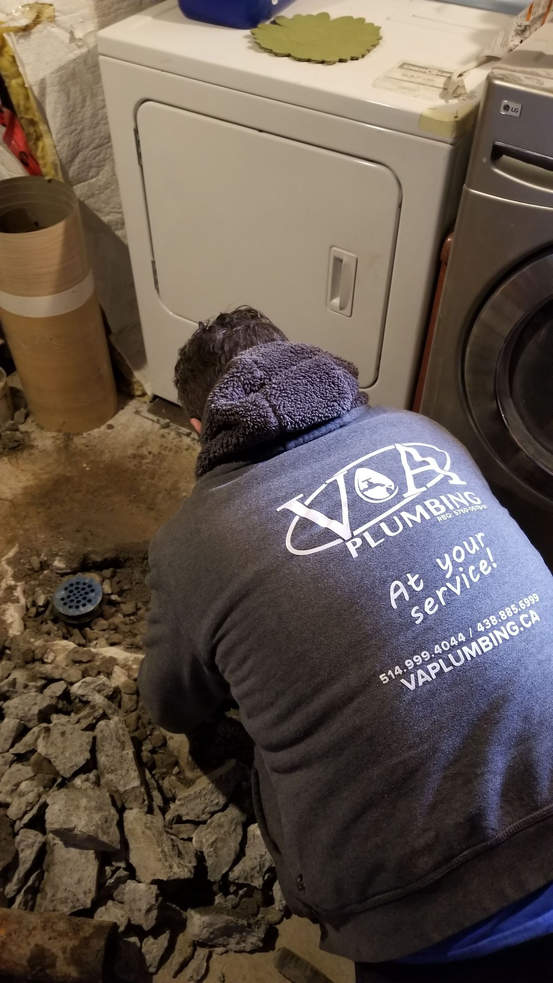 Un homme est agenouillé dans une buanderie à côté d'une laveuse et d'une sécheuse.