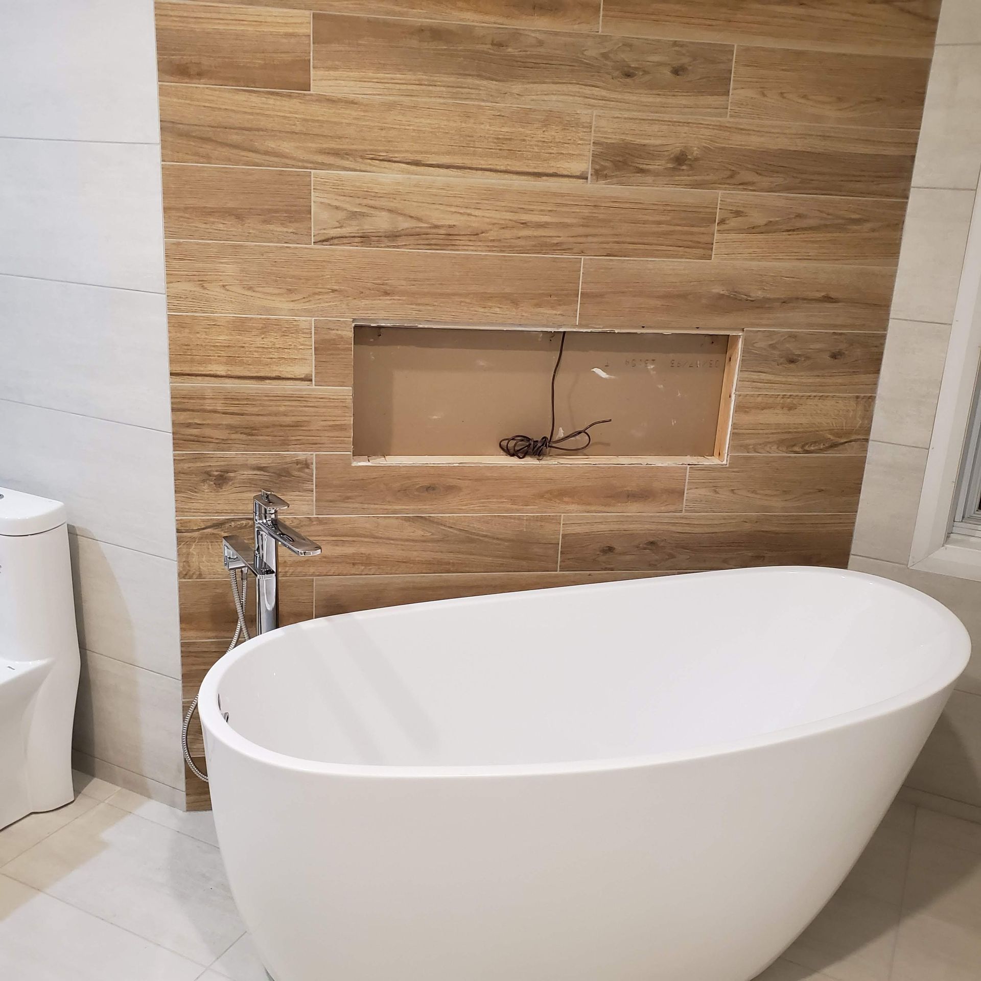 Une baignoire blanche est posée dans une salle de bain à côté de toilettes.