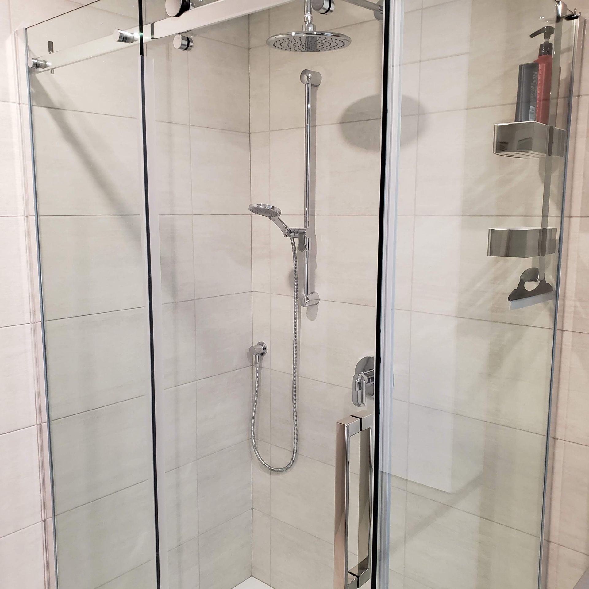 Une douche avec une porte coulissante en verre et une pomme de douche