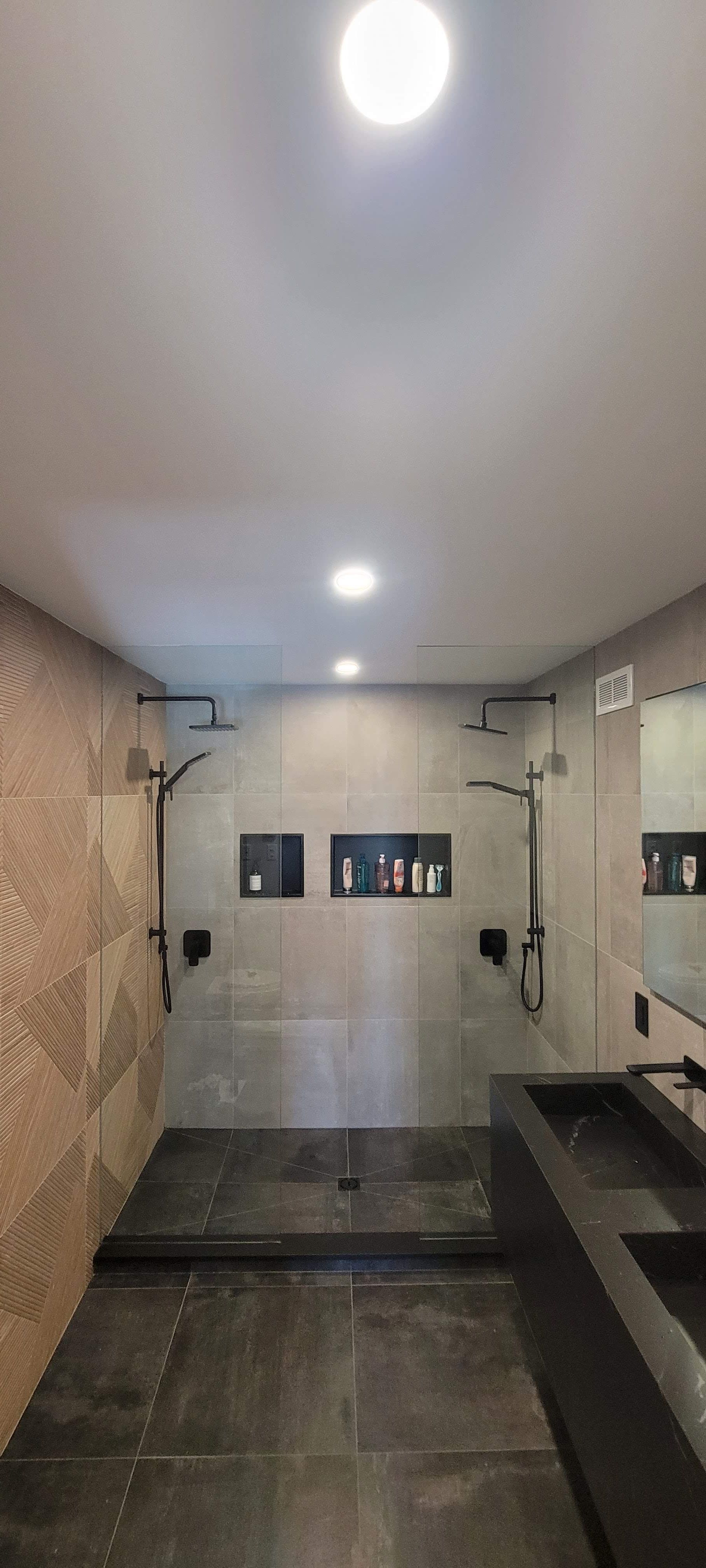 Une salle de bain avec une douche à l'italienne et deux vasques.