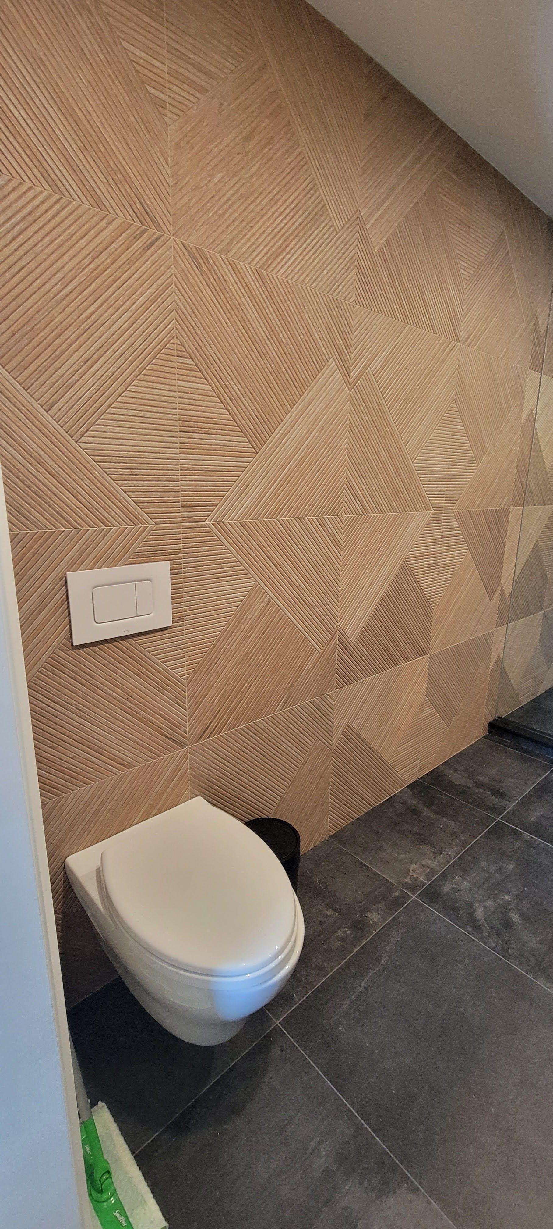 Une toilette est posée sur un sol carrelé dans une salle de bain.