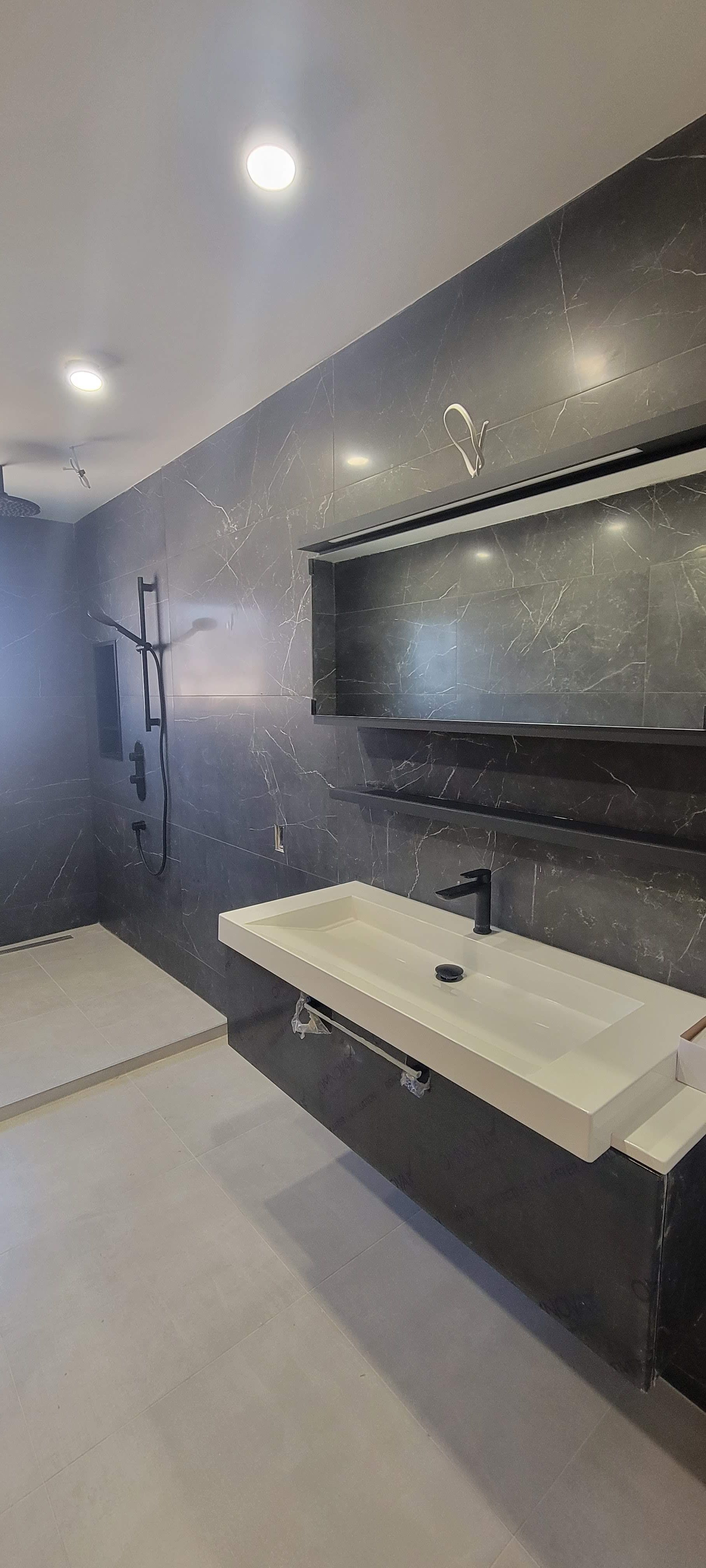 Une salle de bain avec lavabo, douche et miroir.