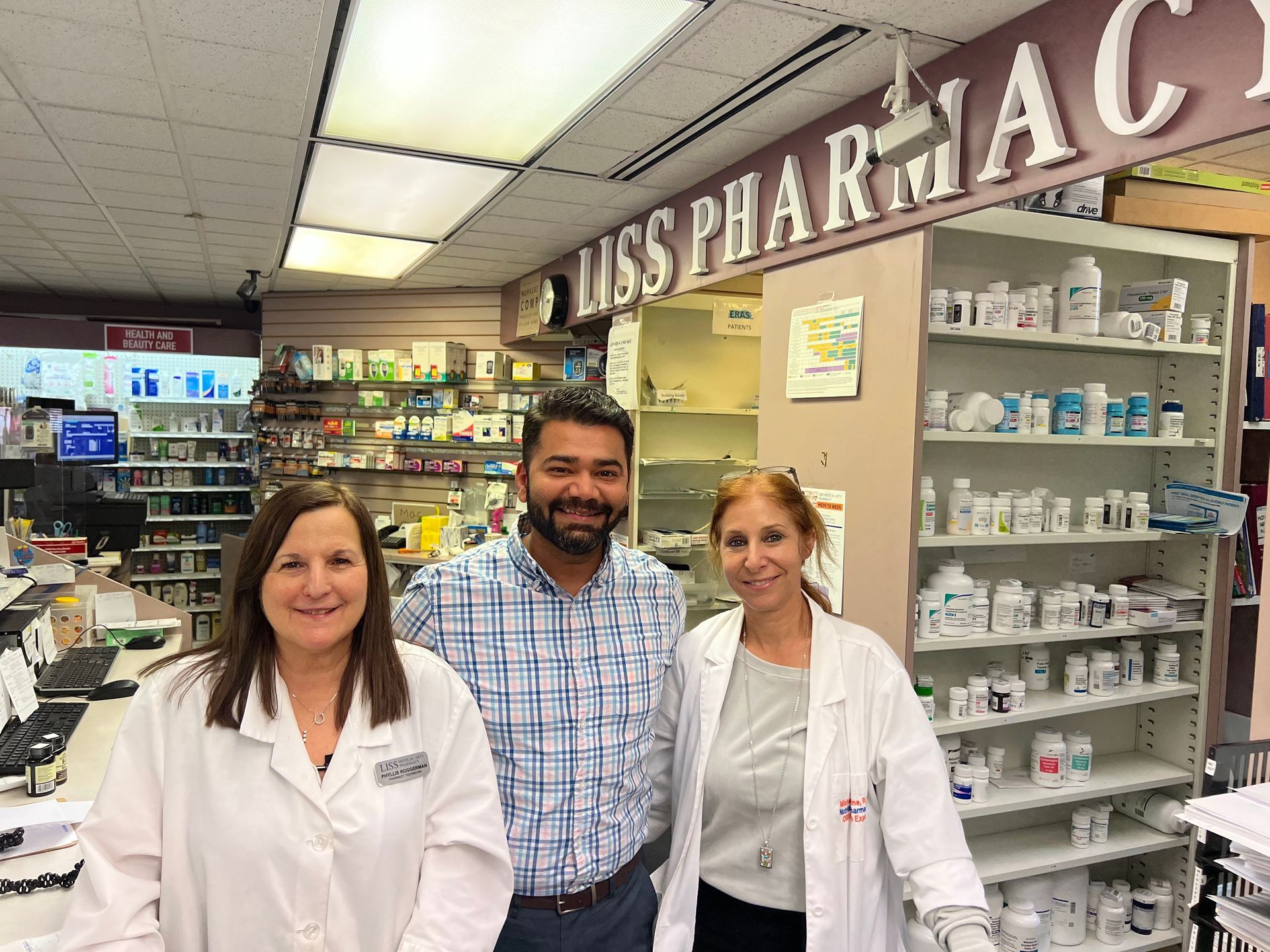 Friendly Pharmacists are posing for a picture in a pharmacy.