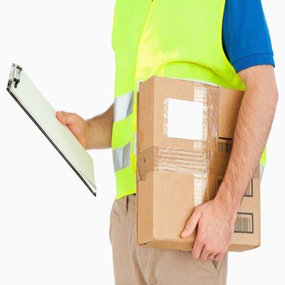 A man in a yellow vest is holding a box and a clipboard