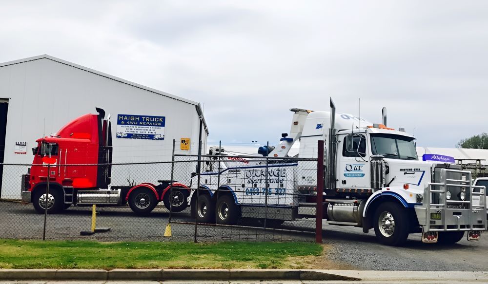 Red and White Semi-Trucks Parked Near a White Building — Haigh Truck & 4WD Repairs In Orange, NSW