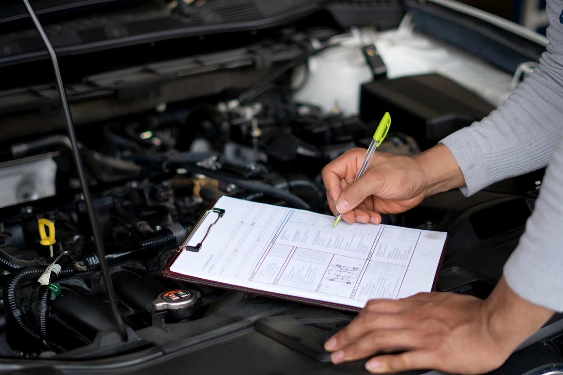 Mechanic Writing on a Clipboard While Inspecting a Car Engine Bay — Haigh Truck & 4WD Repairs In Orange, NSW