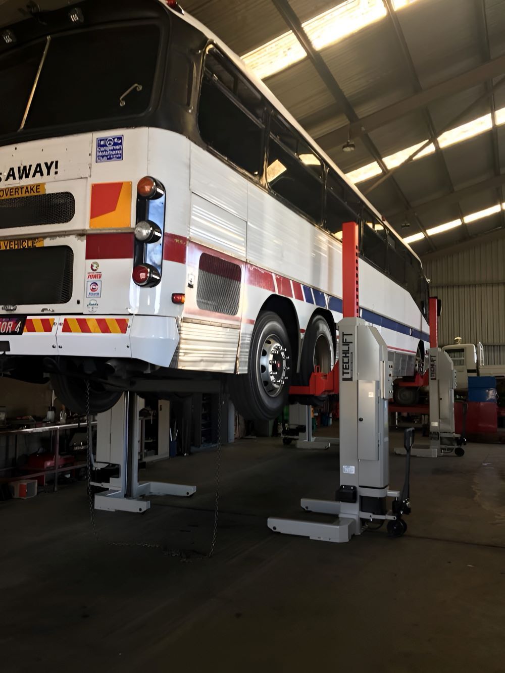 A Bus Is Raised on A Lift Inside a Repair Shop — Haigh Truck & 4WD Repairs In Orange, NSW