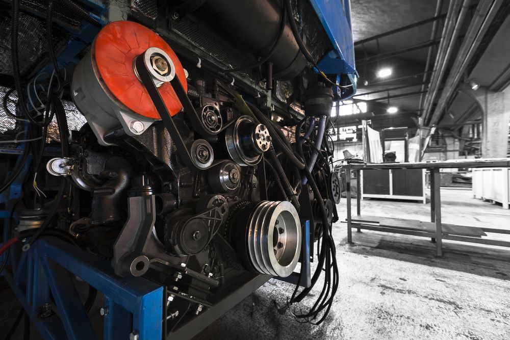 Engine With Belts and Pulleys, Red and Black, in a Factory Setting — Haigh Truck & 4WD Repairs In Orange, NSW